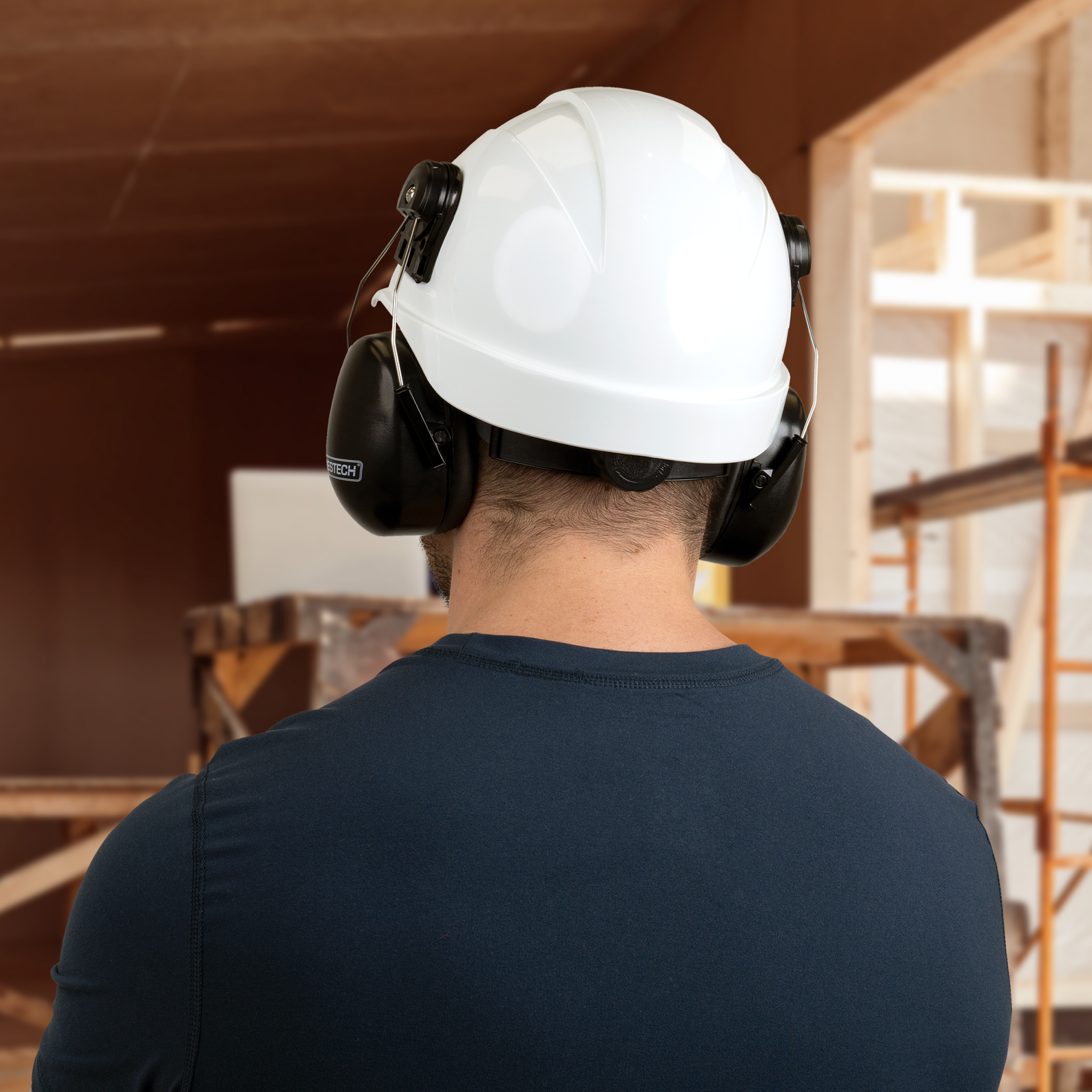 Worker wearing a ANSI compliant cap style hard hat with hearing protection for construction