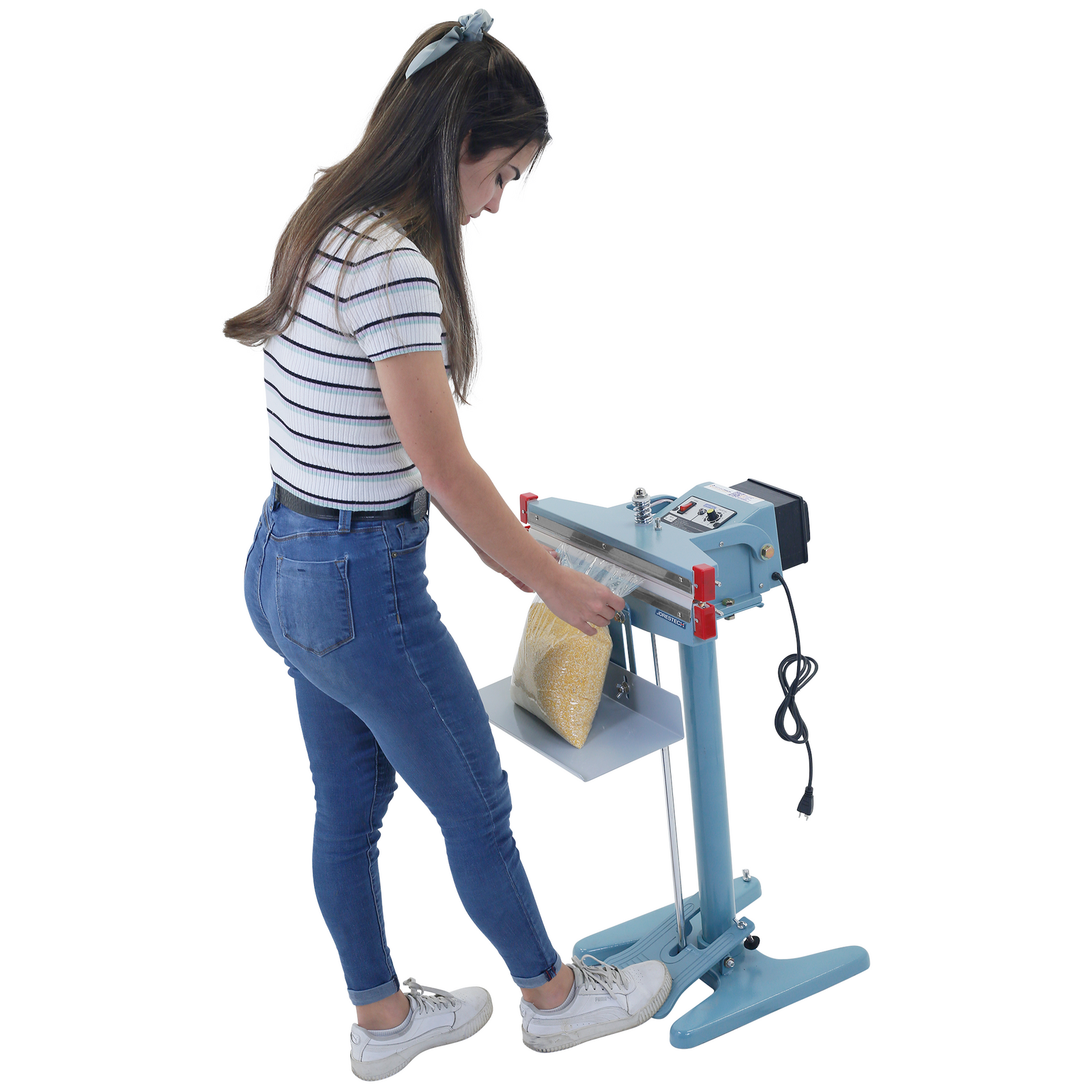 A woman pressing the foot pedal of the double heat impulse sealer to seal a large bag filled with corn