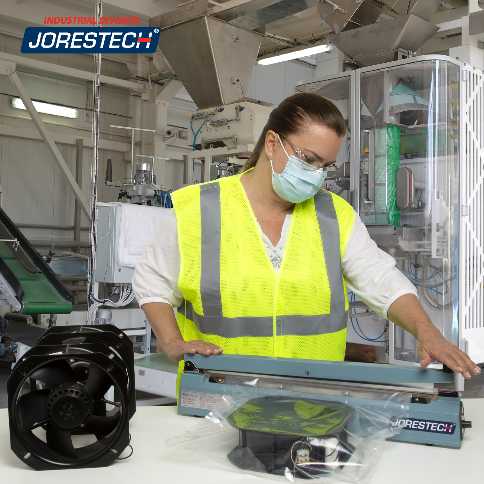 A woman in a factory setting sealing a large heat sealable bag with a fans inside using the JORES TECHNOLOGIES® 20 inch manual impulse sealer. 