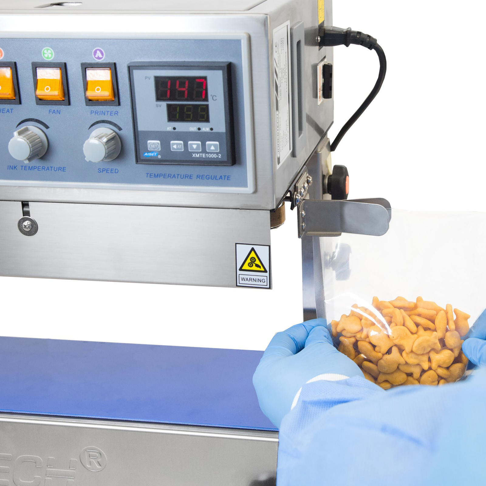 operator wearing blue gloves inserting plastic bag filled with orange crackers into the guide of the JORES TECHNOLOGIES® Stainless steel continuous band sealers