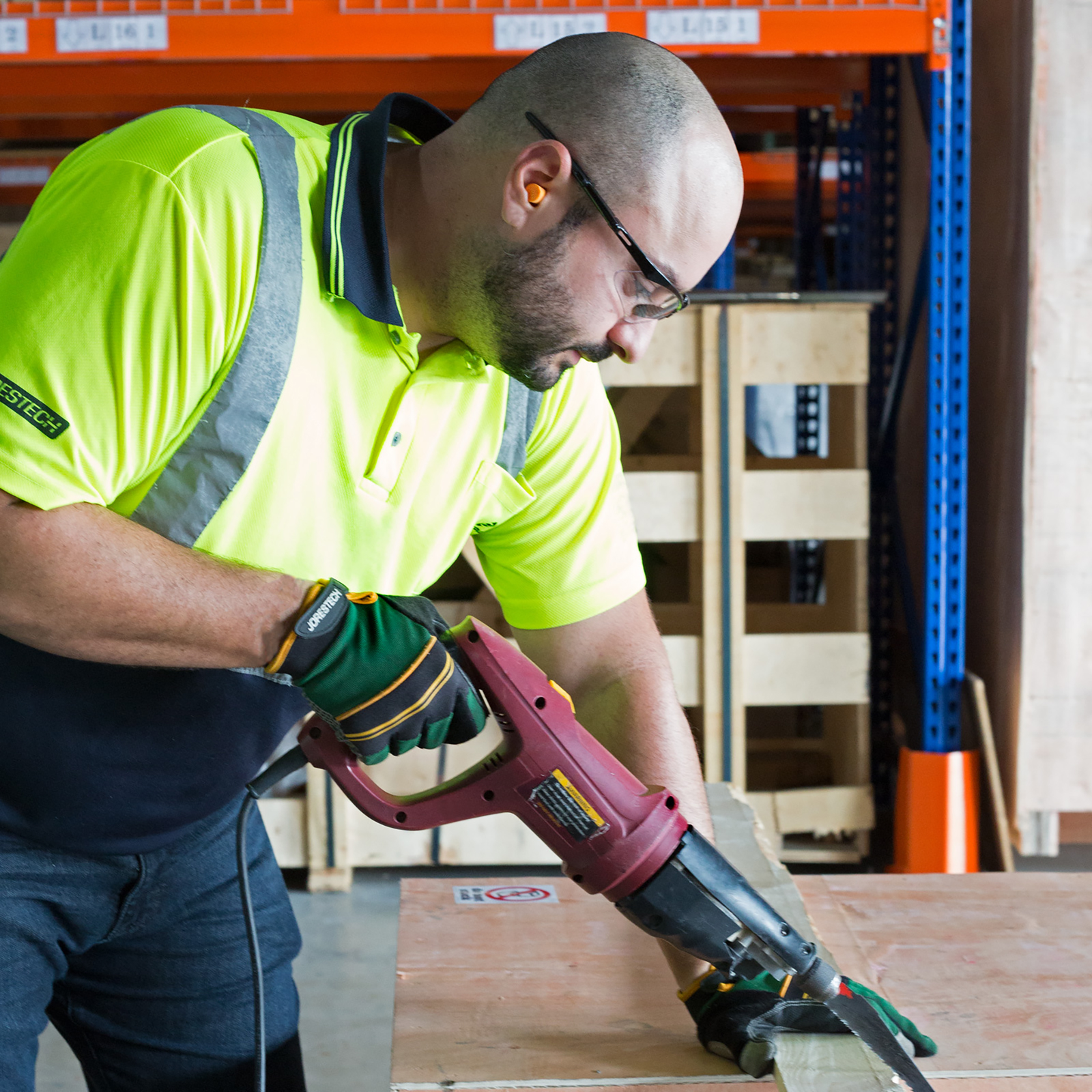 A worker wearing JORESTECH ear plugs to cancel loud noises of a power tool to cut wood.