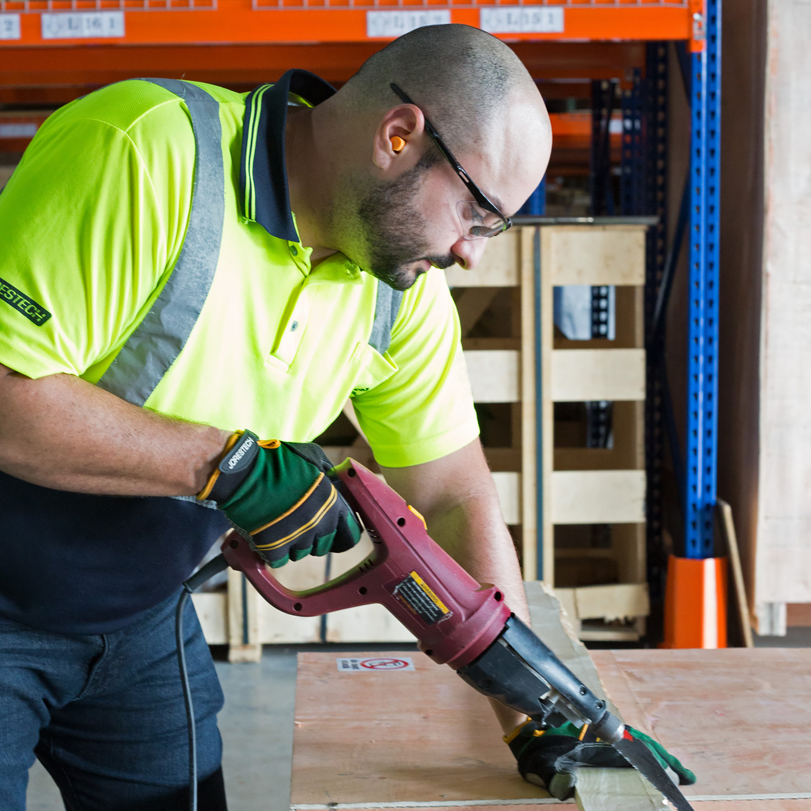 A worker wearing JORESTECH foam earplugs for noise cancelation while operating a loud power tool to cut wood.