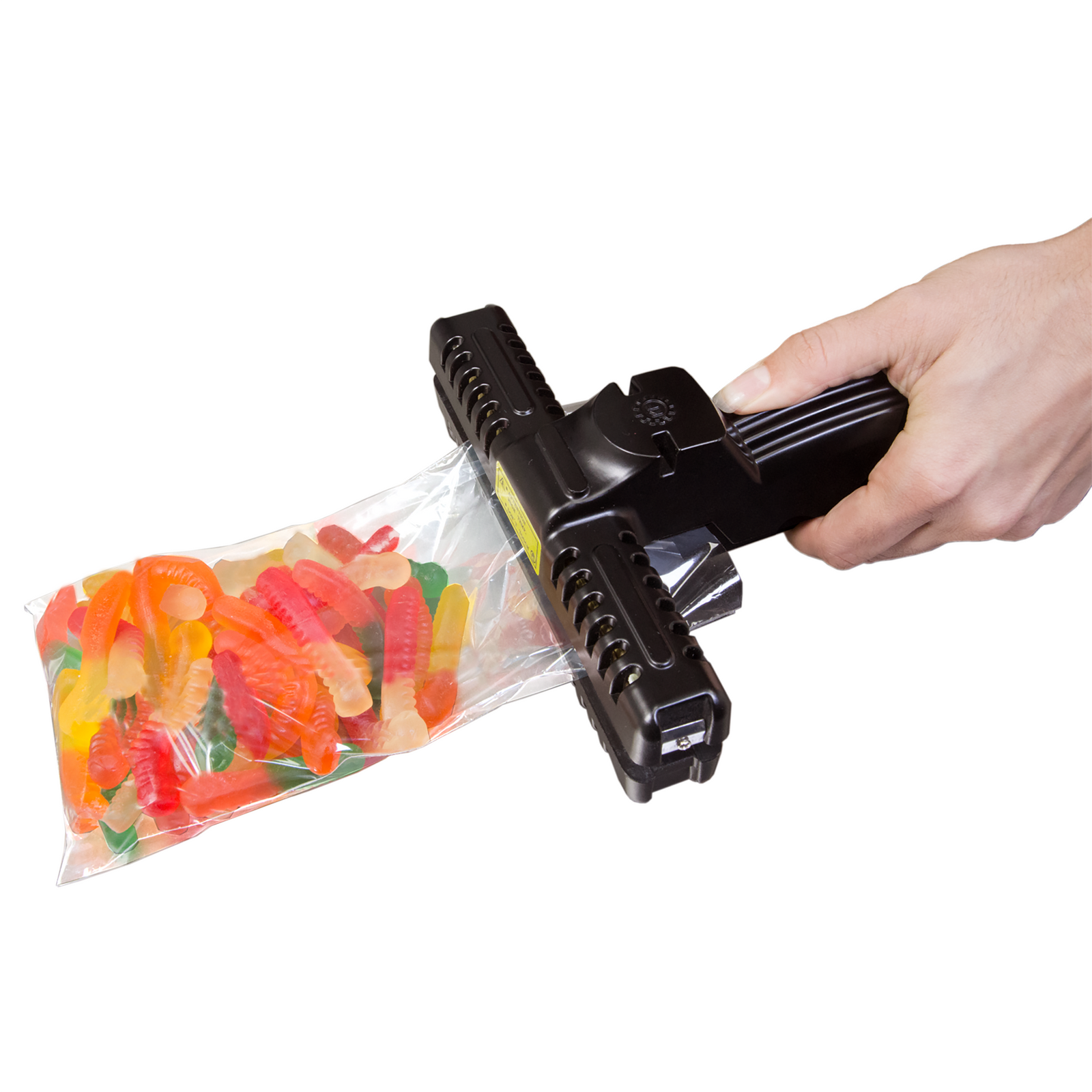 The hand of a person with a 6 inch constant heat hand held crimp wide sealer sealing a bag filled with candies