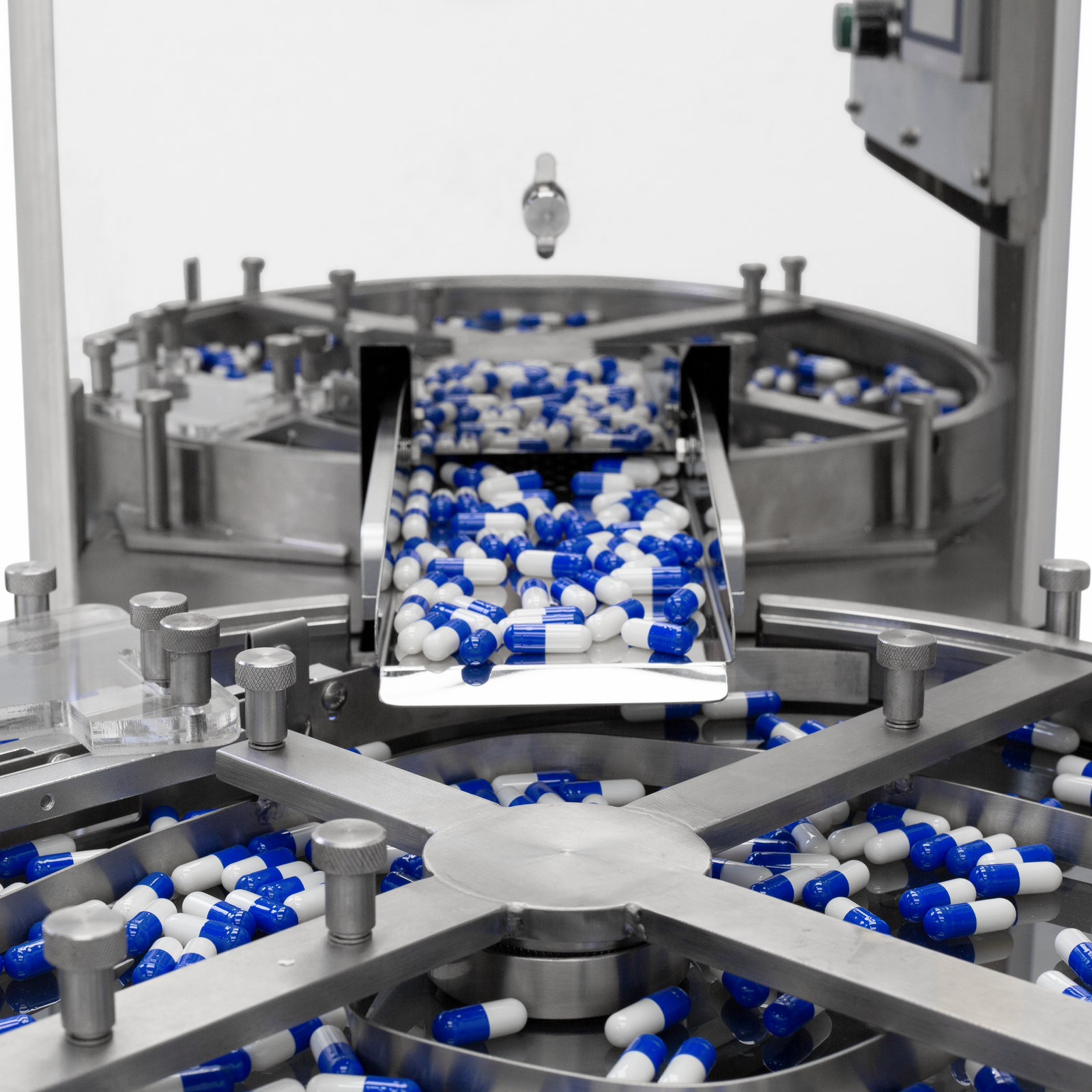 How pills exit from a large stainless steel hopper of the JORES TECHNOLOGIES® pill counter and fall into a circular segmented tray.  