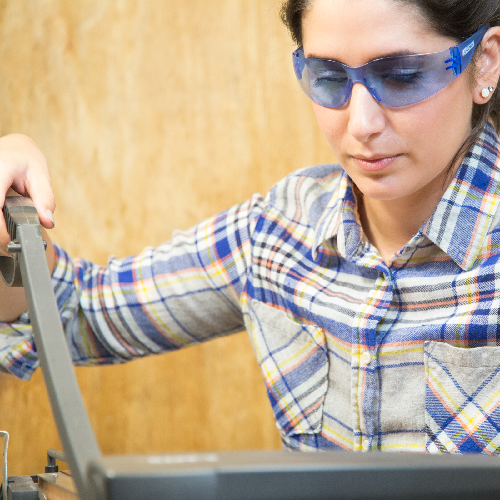 A woman wearing the all blue JORESTECH safety glasses with uv protection for high impact protection ANSI compliant while doing a DUI project in her workshop