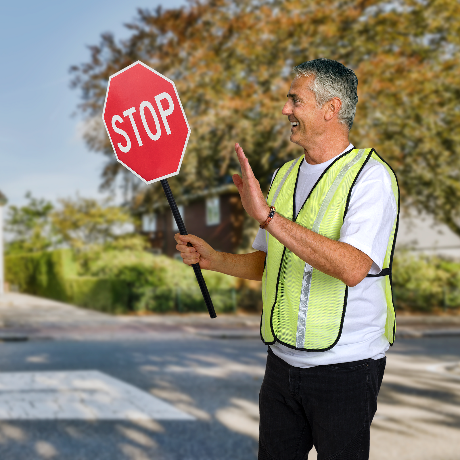 Worker wearing the lime reflective safety vest while directing traffic in a school area