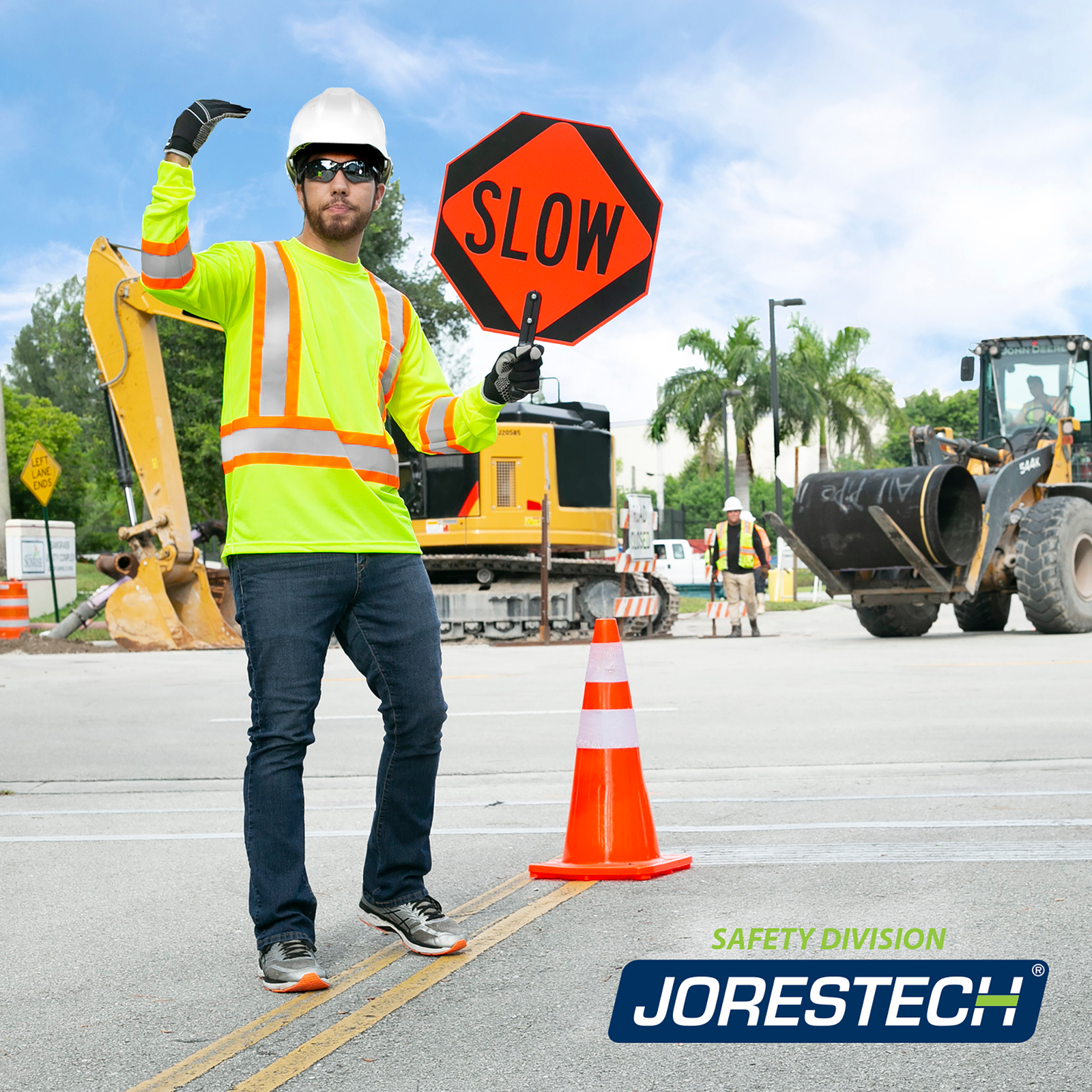 A man wearing the yellow and orange strips JORESTECH safety shirt while directing the traffic because of a large road repair.