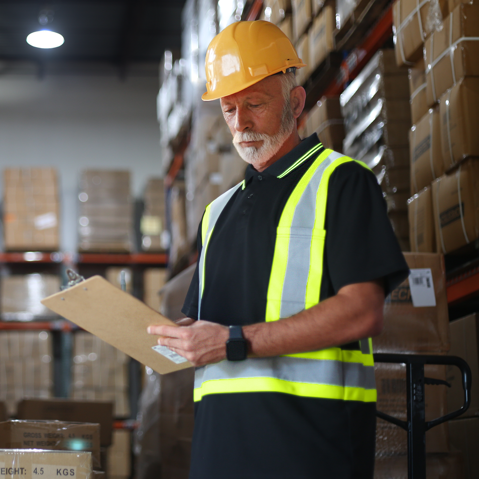 Man wearing the Black Hi Vis polo shirt ANSI compliant class 1 type O while working inside a warehouse during picking up merchandise 