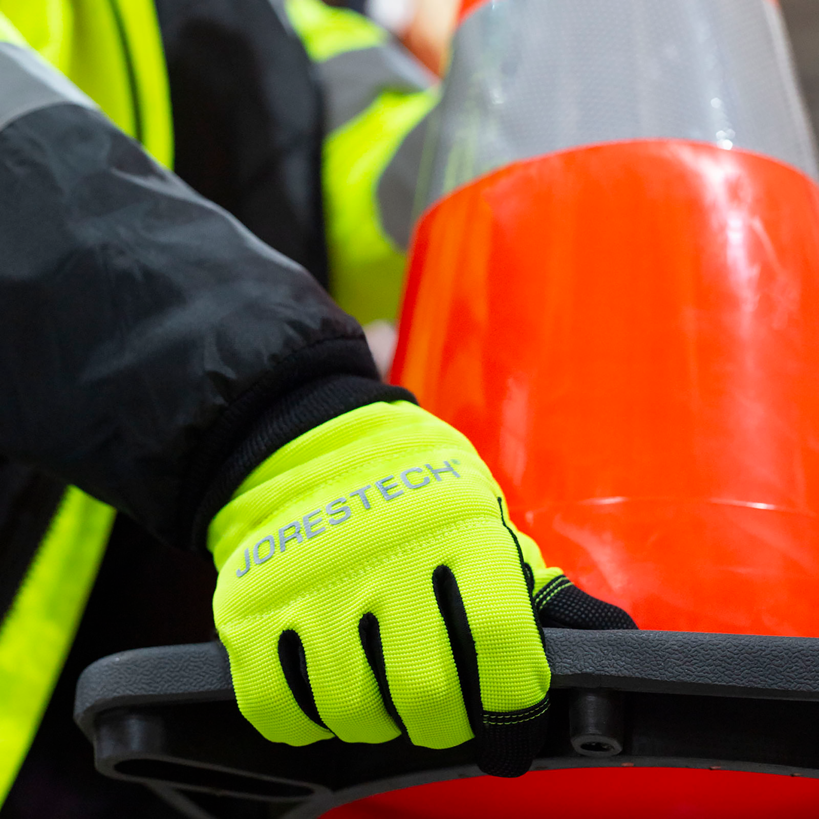 Person wearing the hi-vis multipurpose safety gloves while carrying a street cone