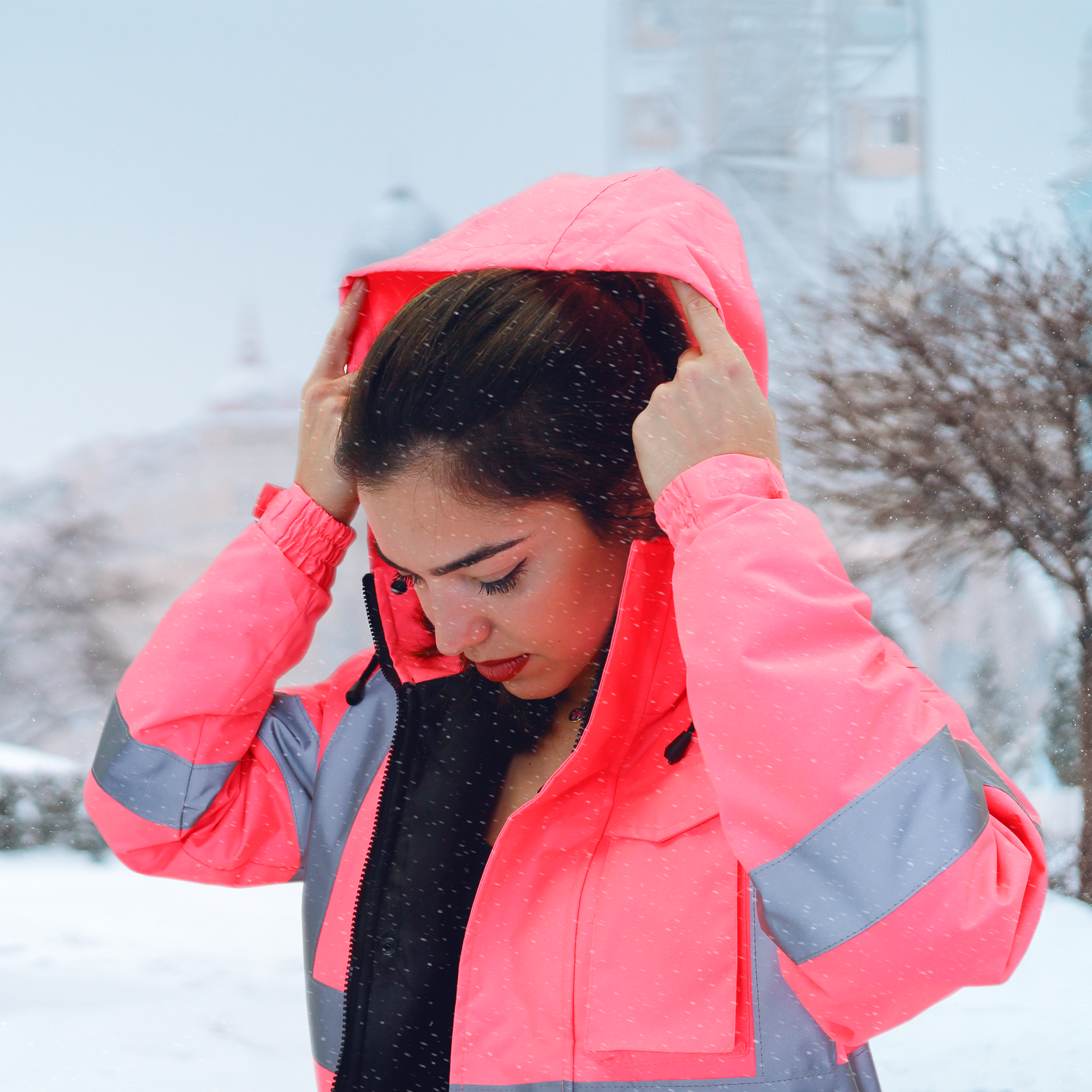 Woman in the snow wearing the hi-vis safety jacket in pink with reflective strips 