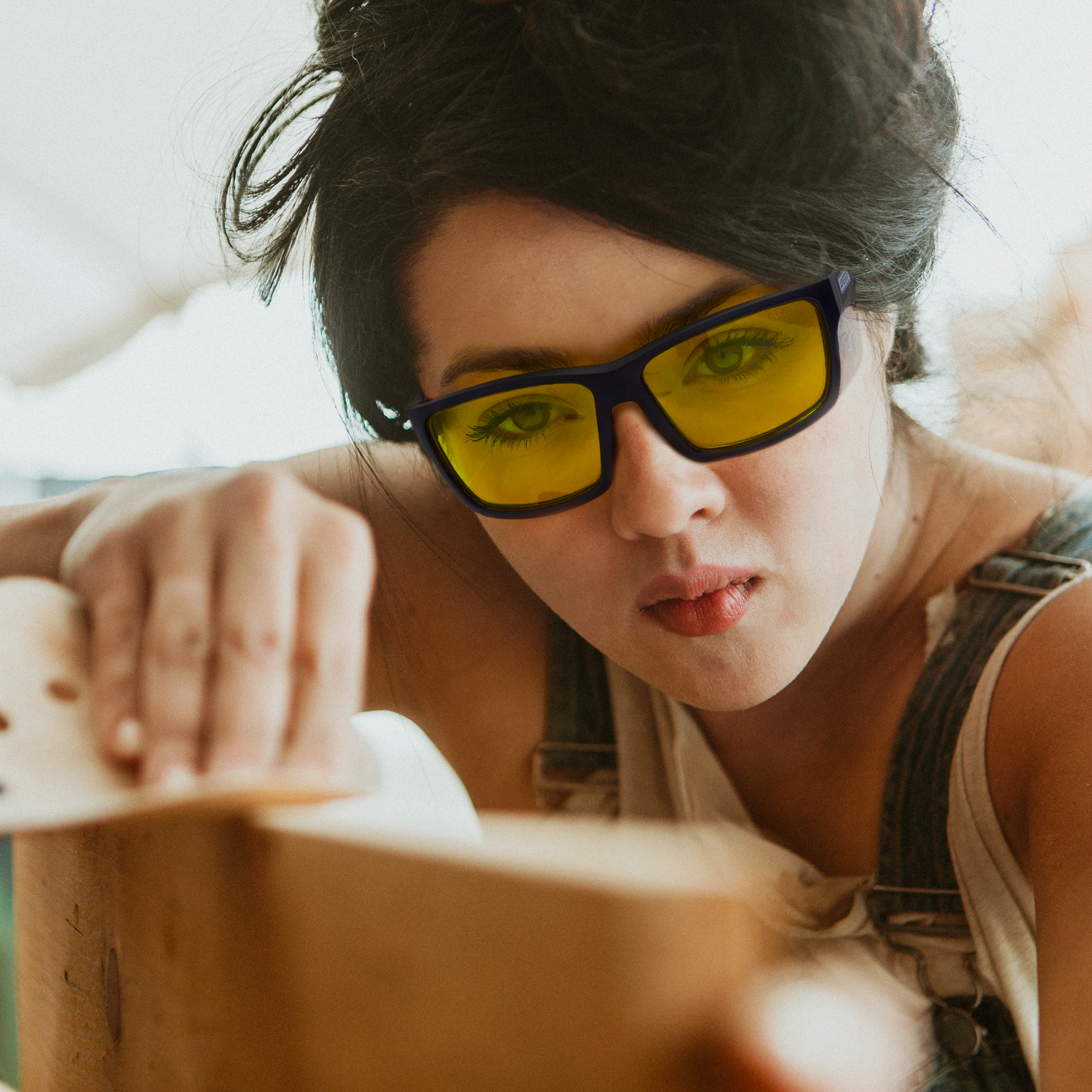 Image of a woman wearing the yellow JORESTECH safety glasses with side shields for high impact protection while sculpting a large piece of wood in a DIY project