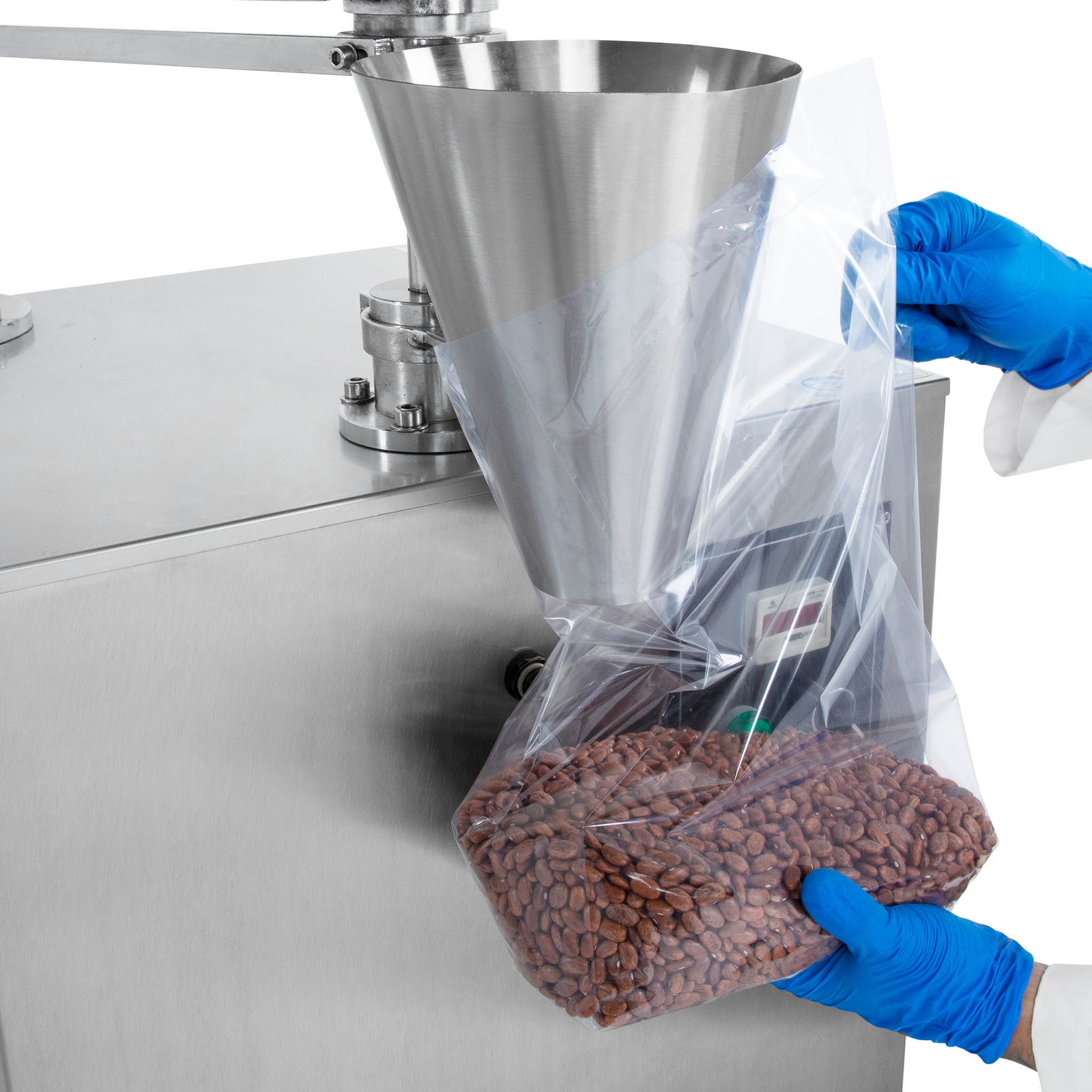 Hands of a worker holding a clear plastic bag under the dispensing cone of the semi automatic volumetric filler. Filling machine releases 2000ml of free-flowing red beans with accuracy