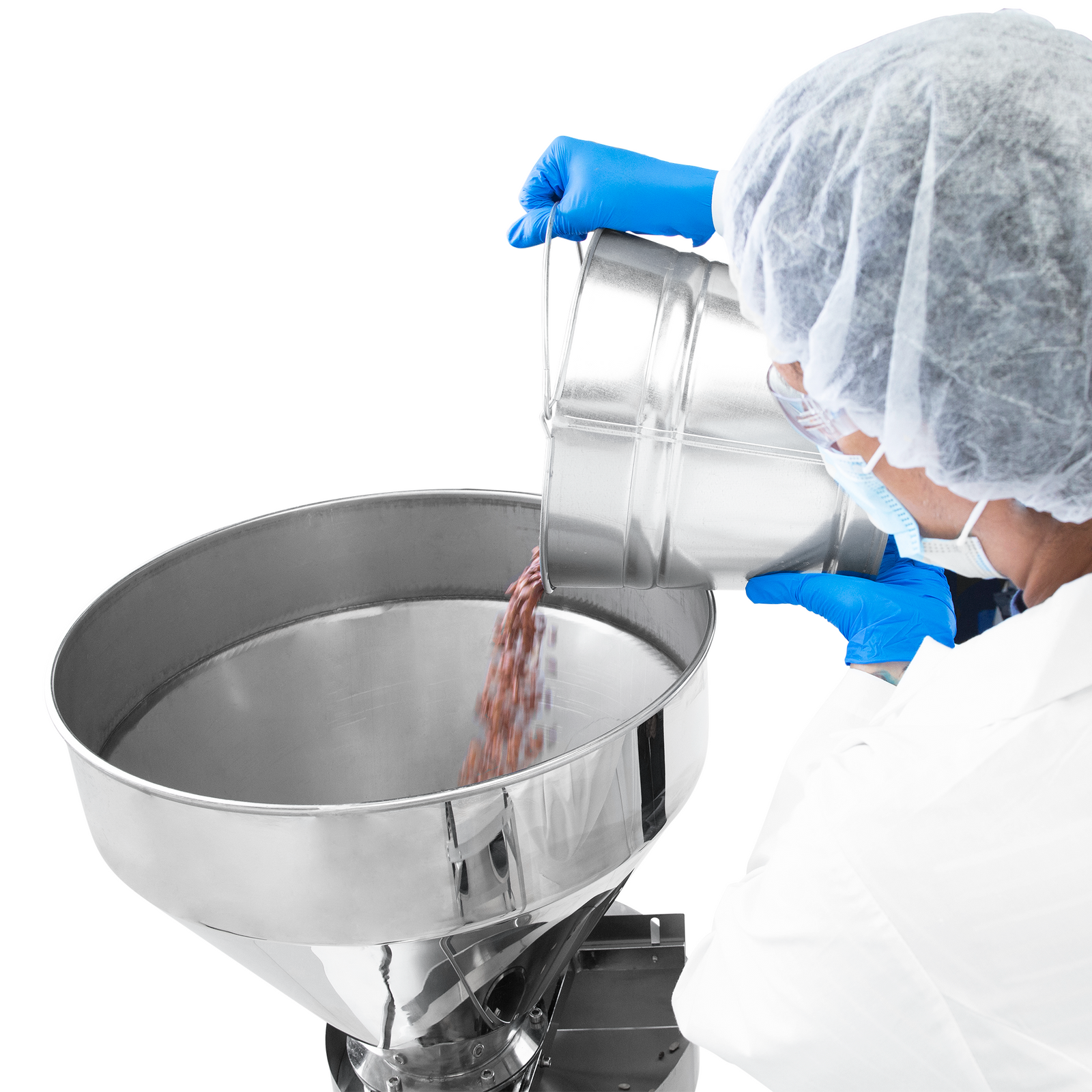 A worker wearing blue nitrile gloves and an assortment of personal protection equipment dispensing beans into the stainless steel hopper of the JORES TECHNOLOGIES® semi automatic volumetric filler