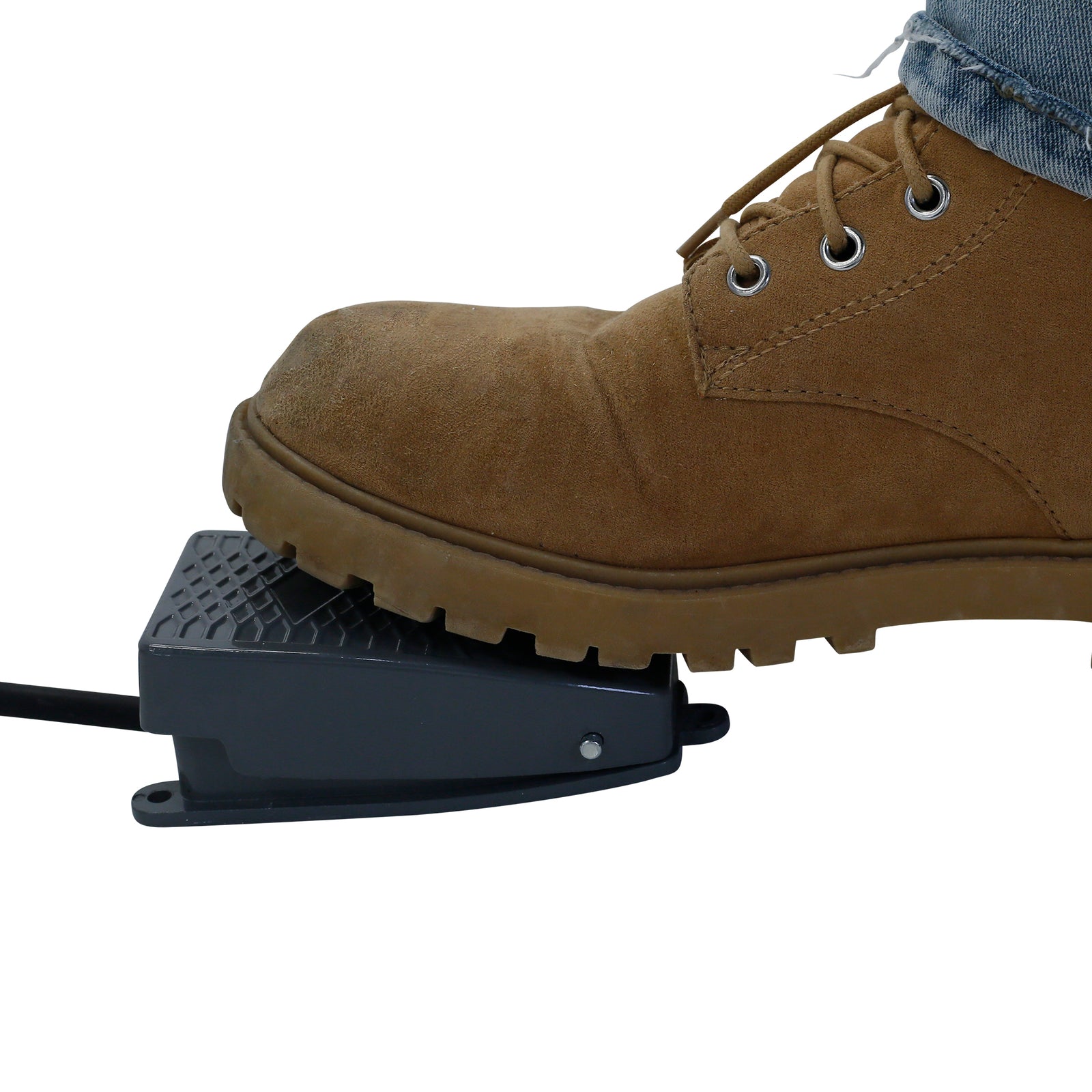 Close up of the ark grey pedal belonging to a JORES TECHNOLOGIES® linear weighing machine. A person wearing brown boots and jeans can be seen pressing down on the pedal to signal the machine to initiate a dispensing cycle