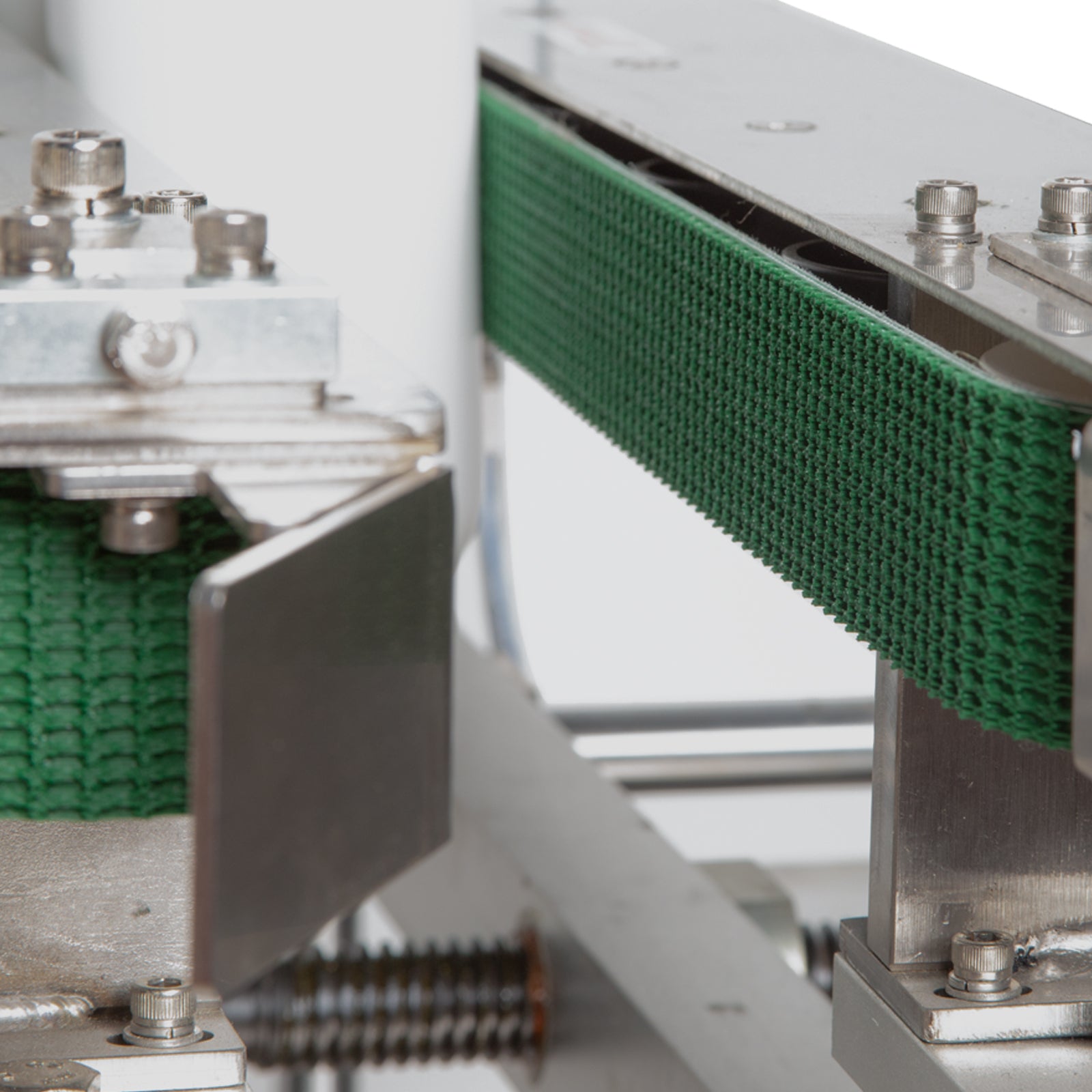 Close up of green side traction belts on the stainless steel JORES TECHNOLOGIES® bottomless conveyor