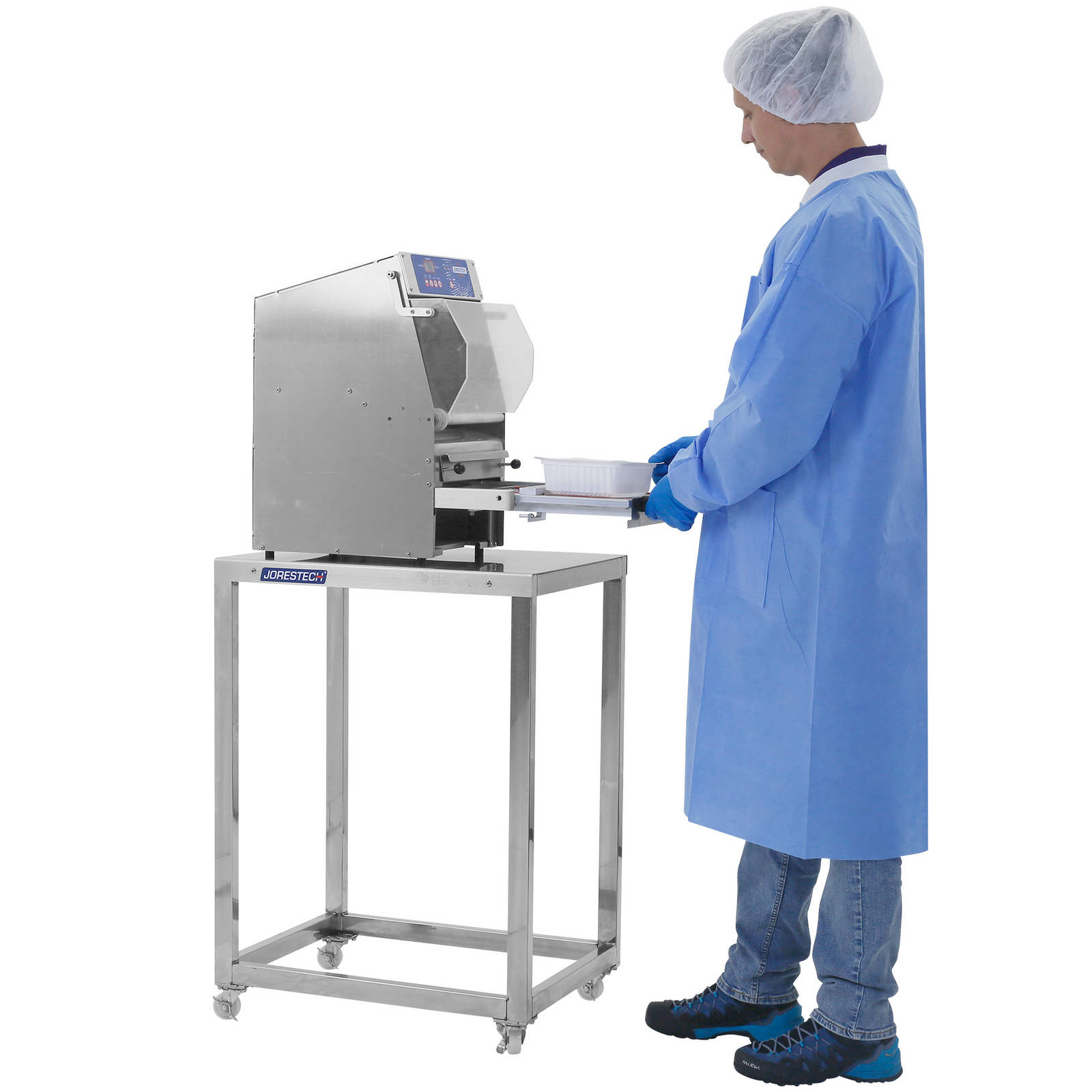 Person wearing disposable PPE clothes and gloves using a tray sealer which is positioned on top of a JORES TECHNOLOGIES® Stainless steel prep work table