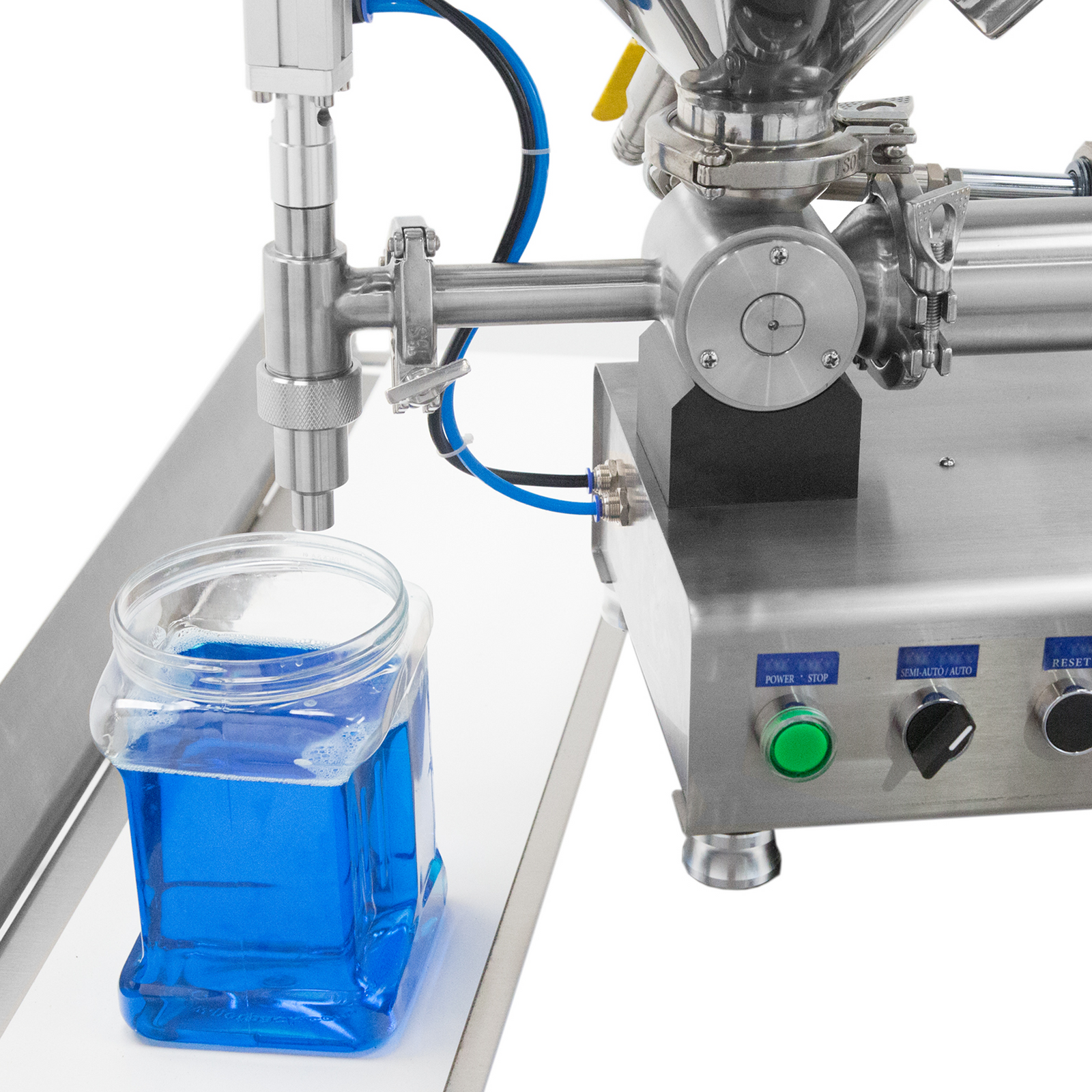 Close up of the non drip nozzle of a JORES TECHNOLOGIES® table top paste piston filler with heated hopper and a clear container with blue liquid after being filled