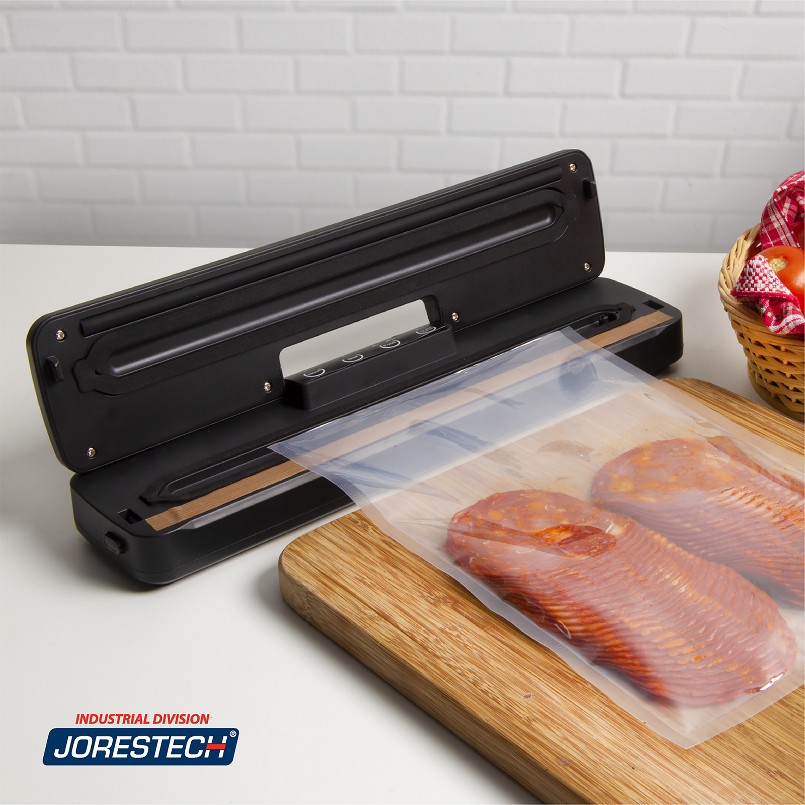 Black JORES TECHNOLOGIES® vacuum sealing machine for home use on a kitchen counter. an embossed vacuum pouch filled with Salamy lays on a wooden board next to the sealing machine, ready to be packaged. 