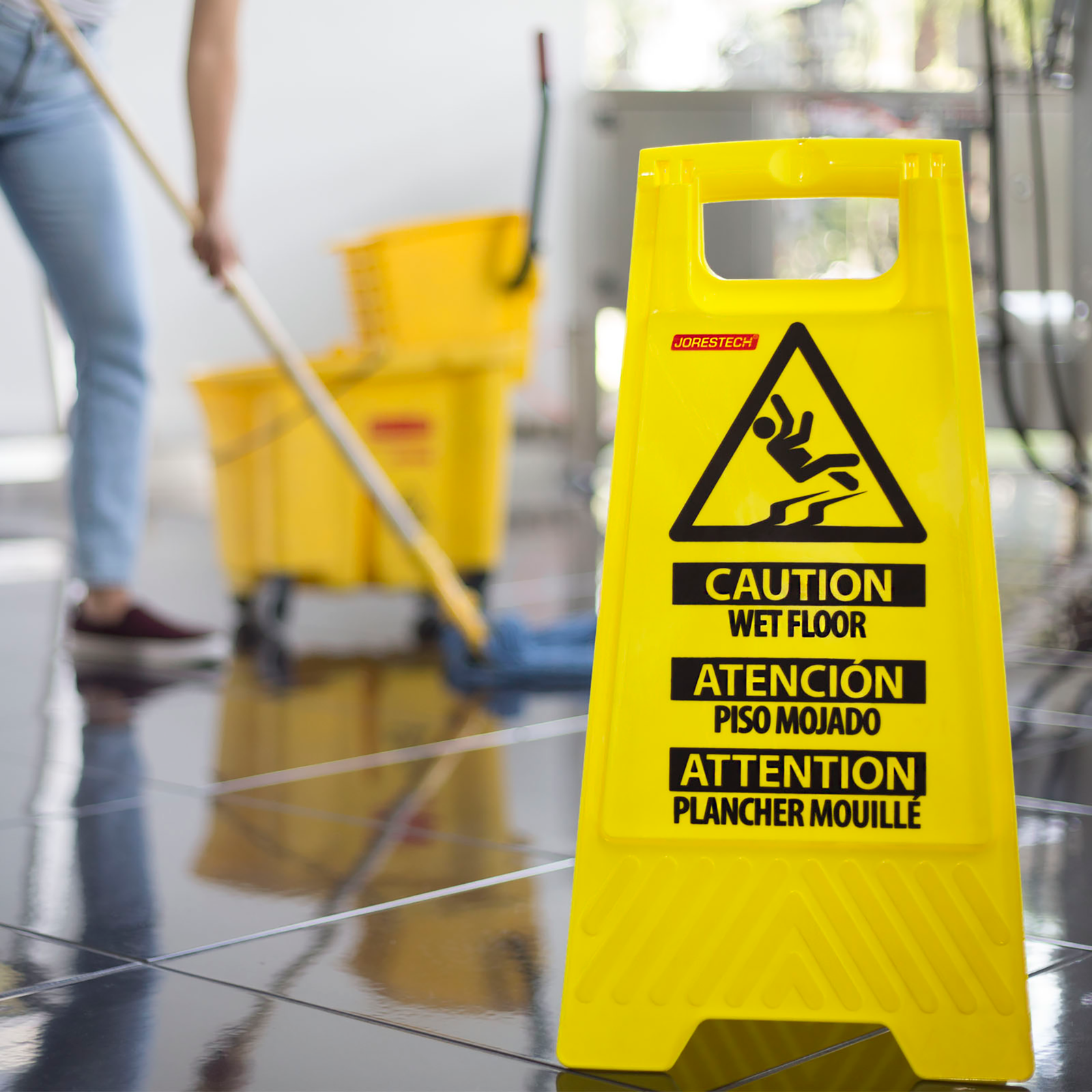 The Jorestech two sided folding wet floor caution stand used while a person is mopping the floor.