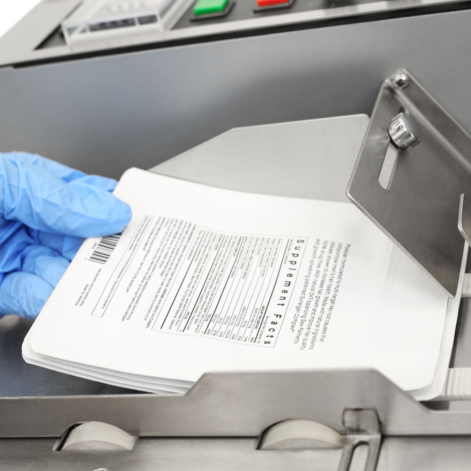 Close up of the hand of a person placing a group of white plastic bags into the JORES TECHNOLOGIES® table top hot ink roll coder so that the machine can start coding