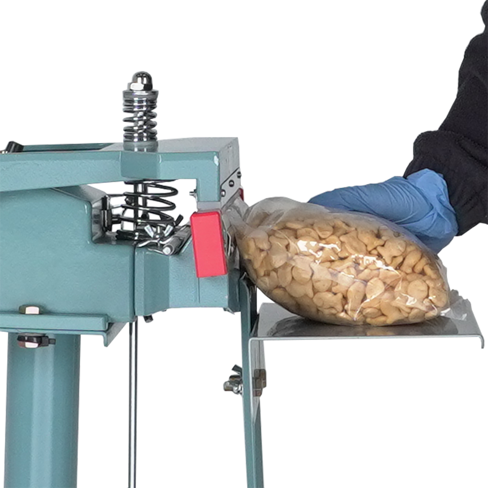 Closeup on a person wearing a black long shirt and blue gloves They are sealing a large bag with fish cookies inside. 