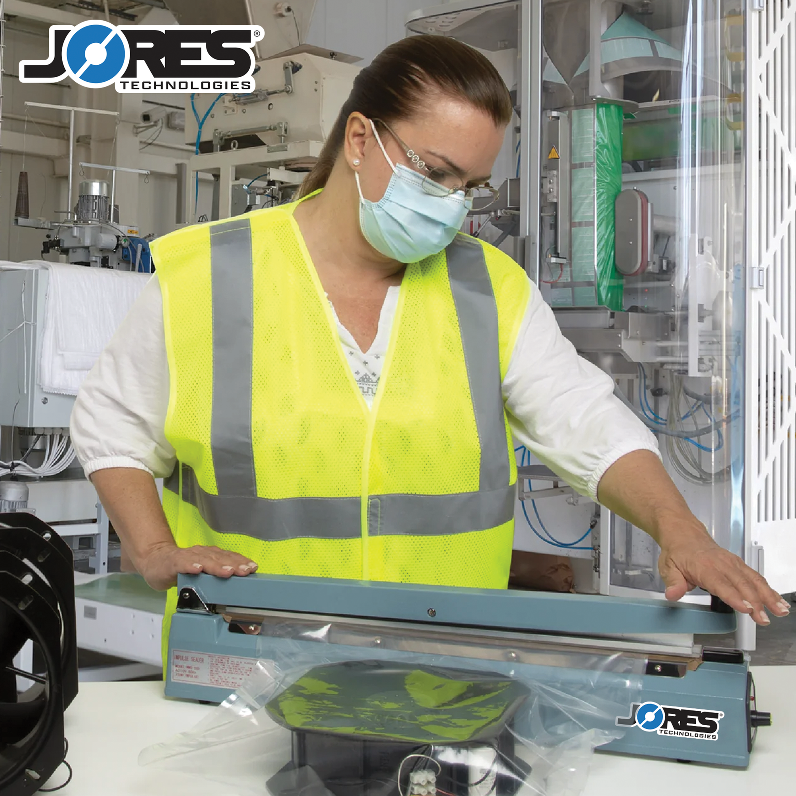 A woman in a factory setting sealing a large heat sealable bag with a fans inside using the JORES TECHNOLOGIES® 20 inch manual impulse sealer. 