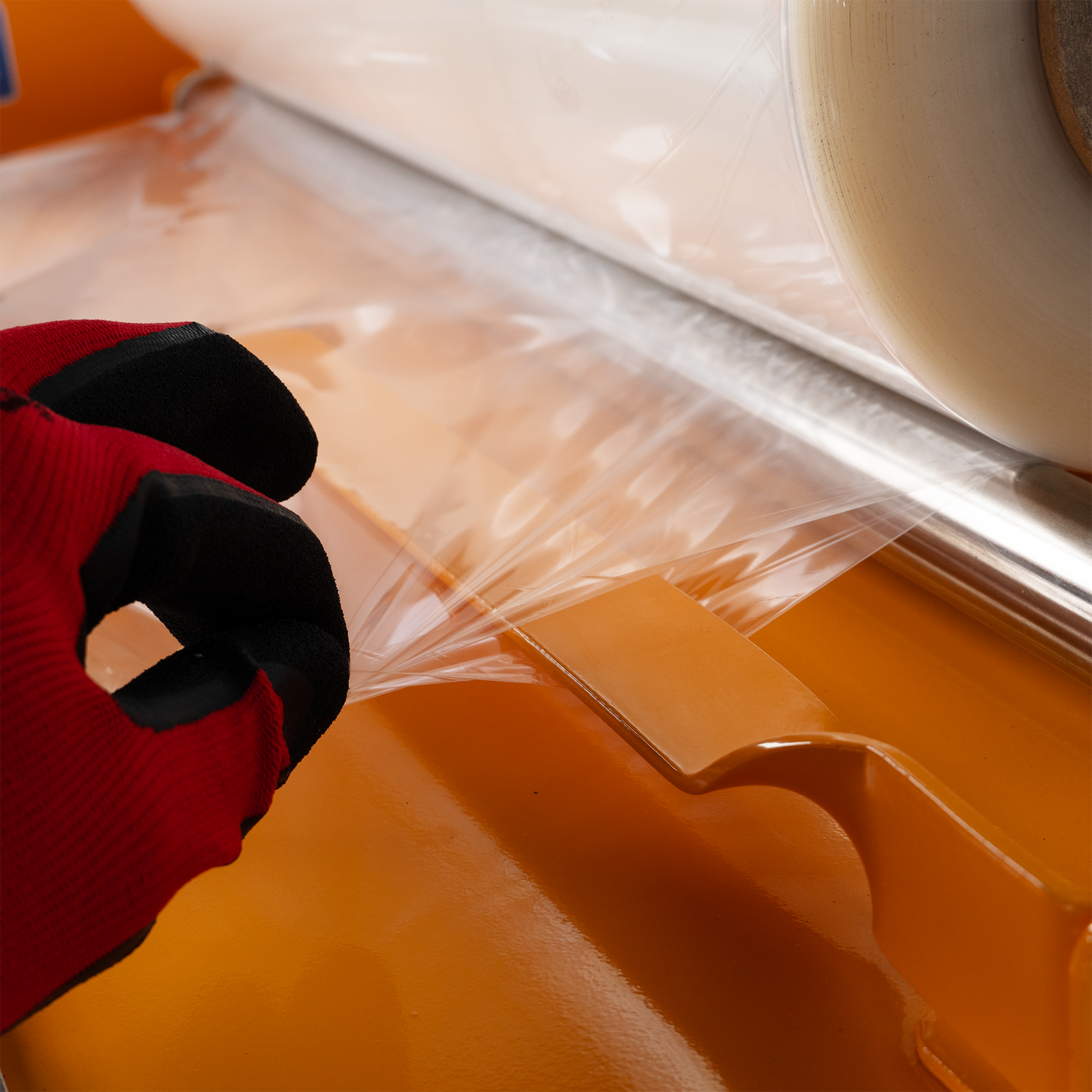 Hand pulling shrink film from a centerfold shrink roll. Shows how the film separating arm keeps both sides of the film neatly separated from each other for an easier packaging experience. Bottom text reads “Film Separator for Centerfold Rolls”. 