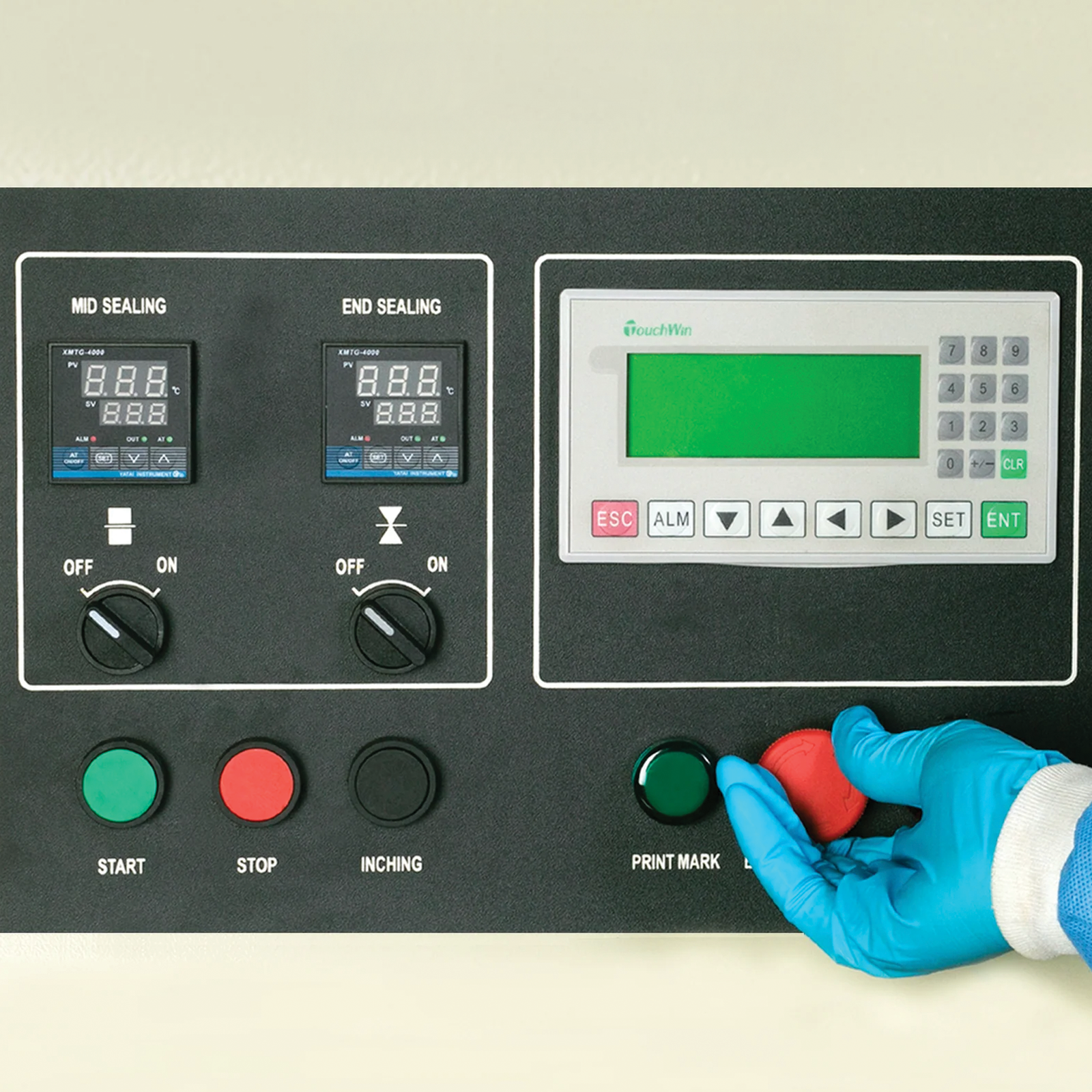 Operator wearing a blue PPE disposable glove is seen operating a Horizontal HFFS flow pack machine. The control panel is shown, and he is about to press the emergency stop button