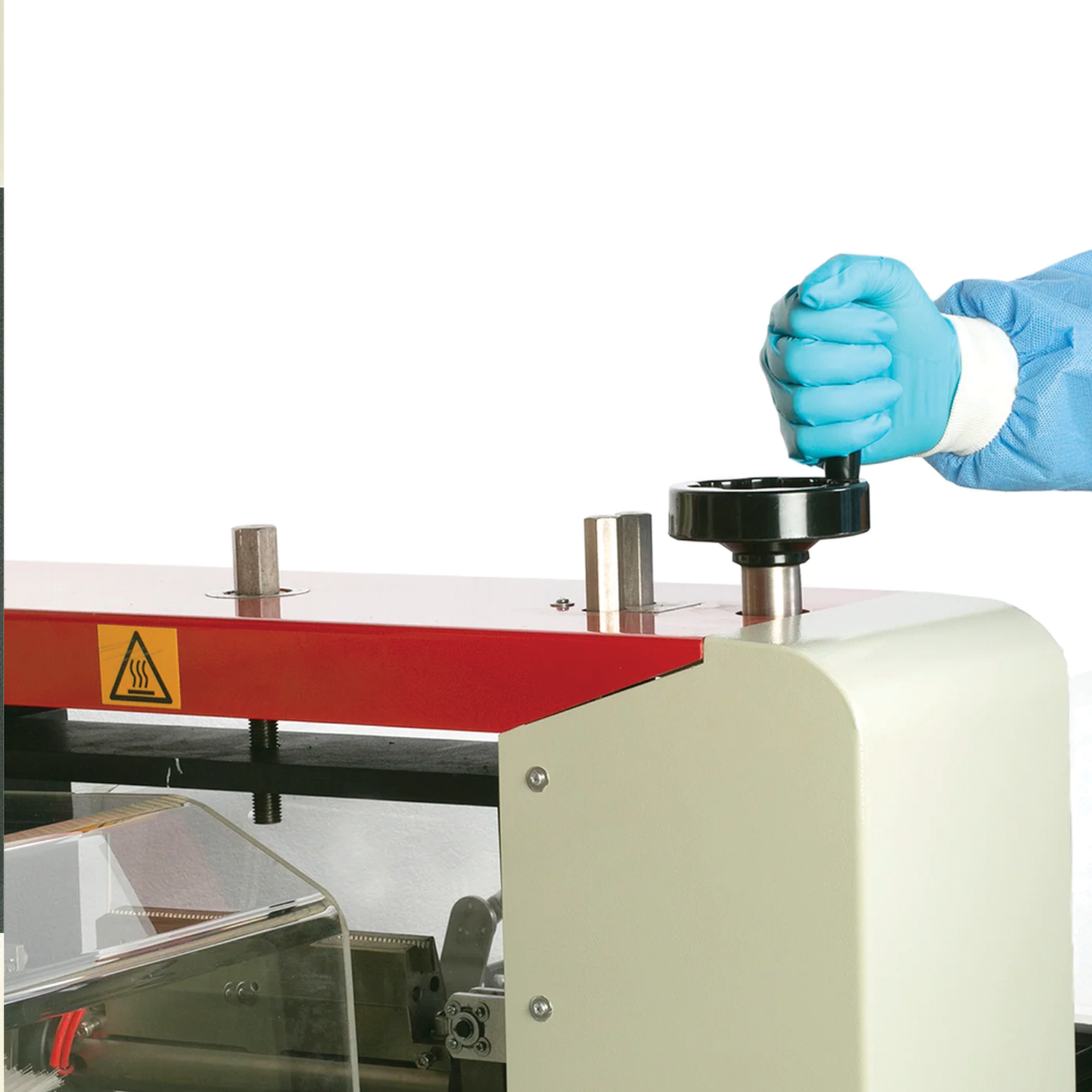 Operator wearing blue PPE disposable gloves and a gown can be seen adjusting the machine's functions by turning a black knob wheel that adjusts height