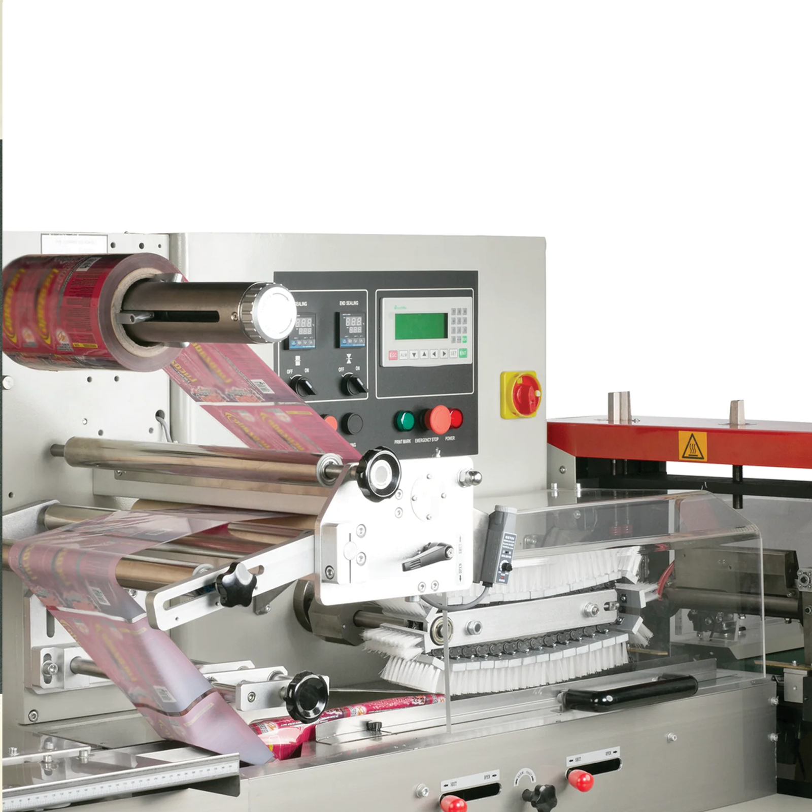 The packaging and sealing area on an automatic HFFS flow pack system. The film roll holder is equipped with a red packaging film roll threaded through the machine and ready for use.  JORES TECHNOLOGIES® industrial logo is shown and a statement that reads User friendly software with touch panel display