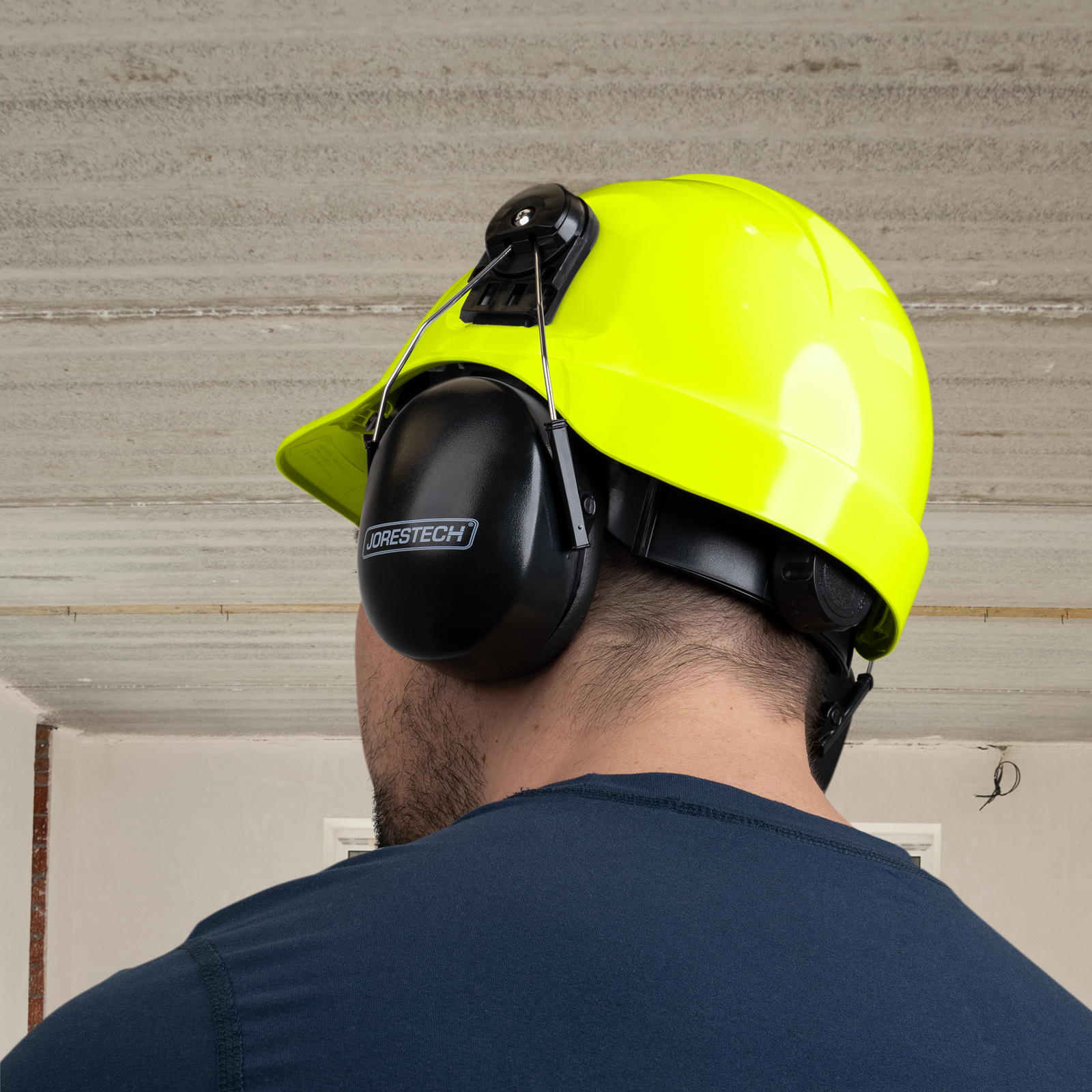 Worker wearing a slotted cap style hard hat with hearing protection for work
