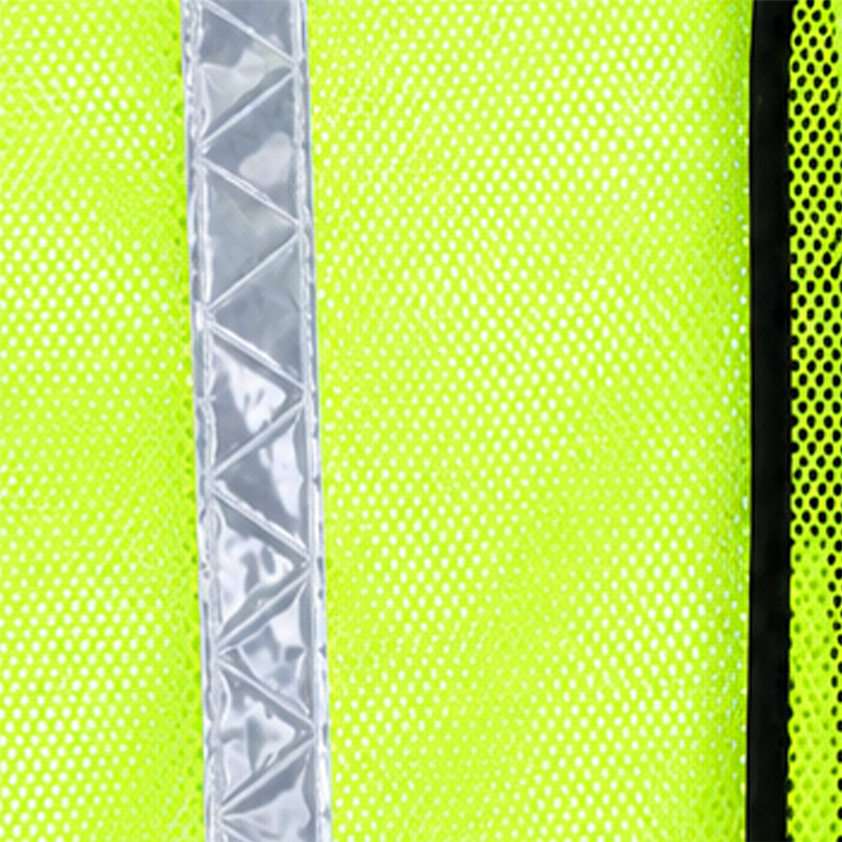 Macro detail shot of a JORESTECH safety vest showing its silver prismatic reflective strip, solid lime-yellow panels, and open-weave breathable mesh.