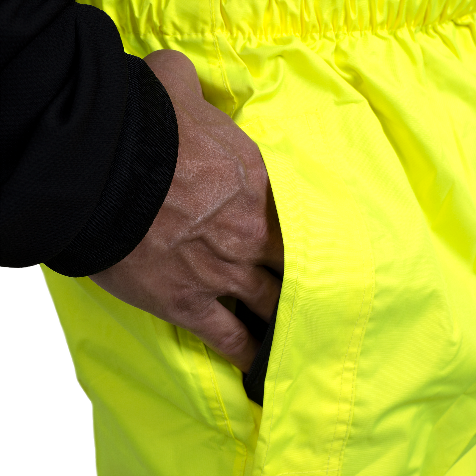 Close up showing a person inserting his hand into the opening of the rain pants to access the pocket of the pants underneath 