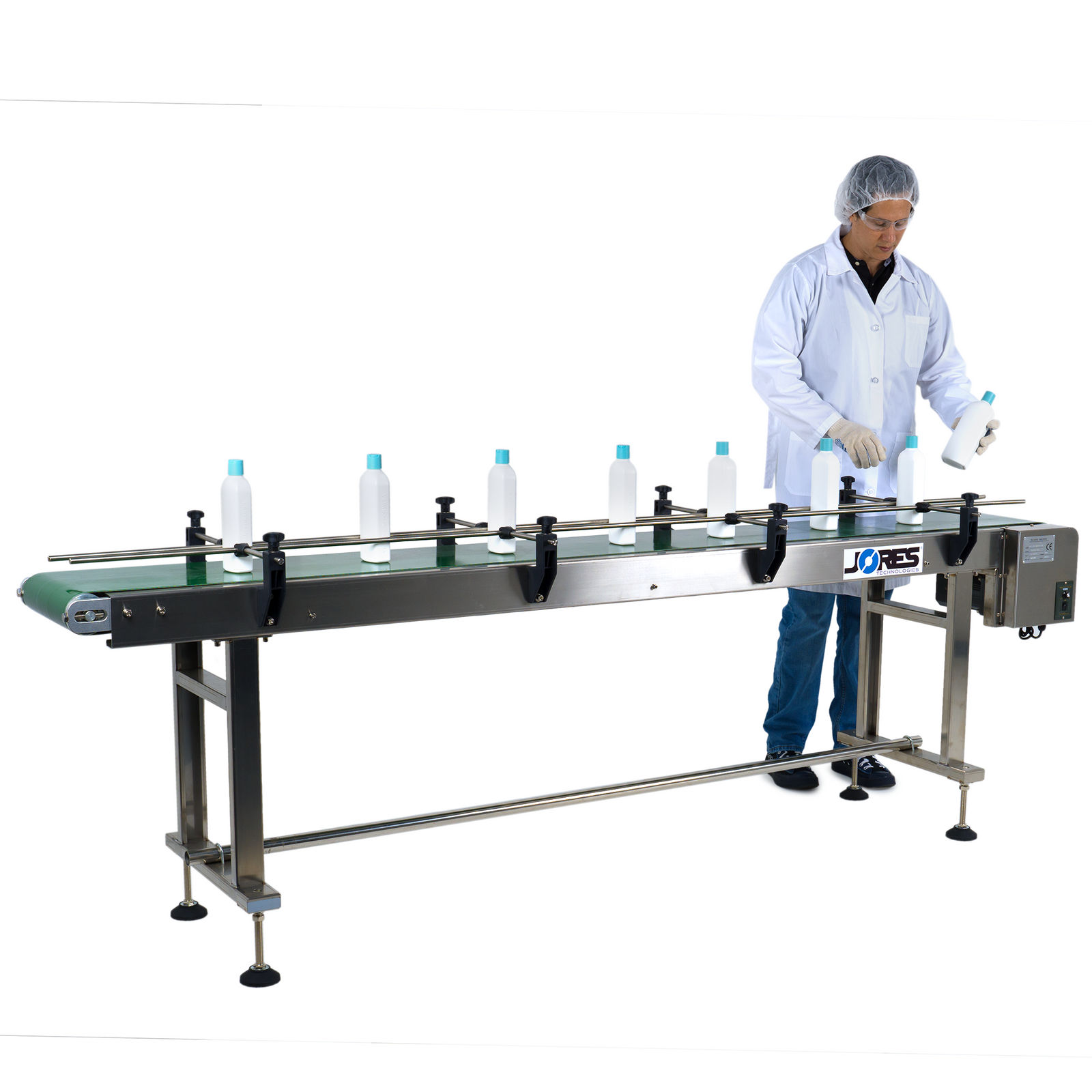 Operator wearing white lab coat and blue gloves adjusting white milk bottles on motorized conveyor with steel frame and motorized belt with side guard rails