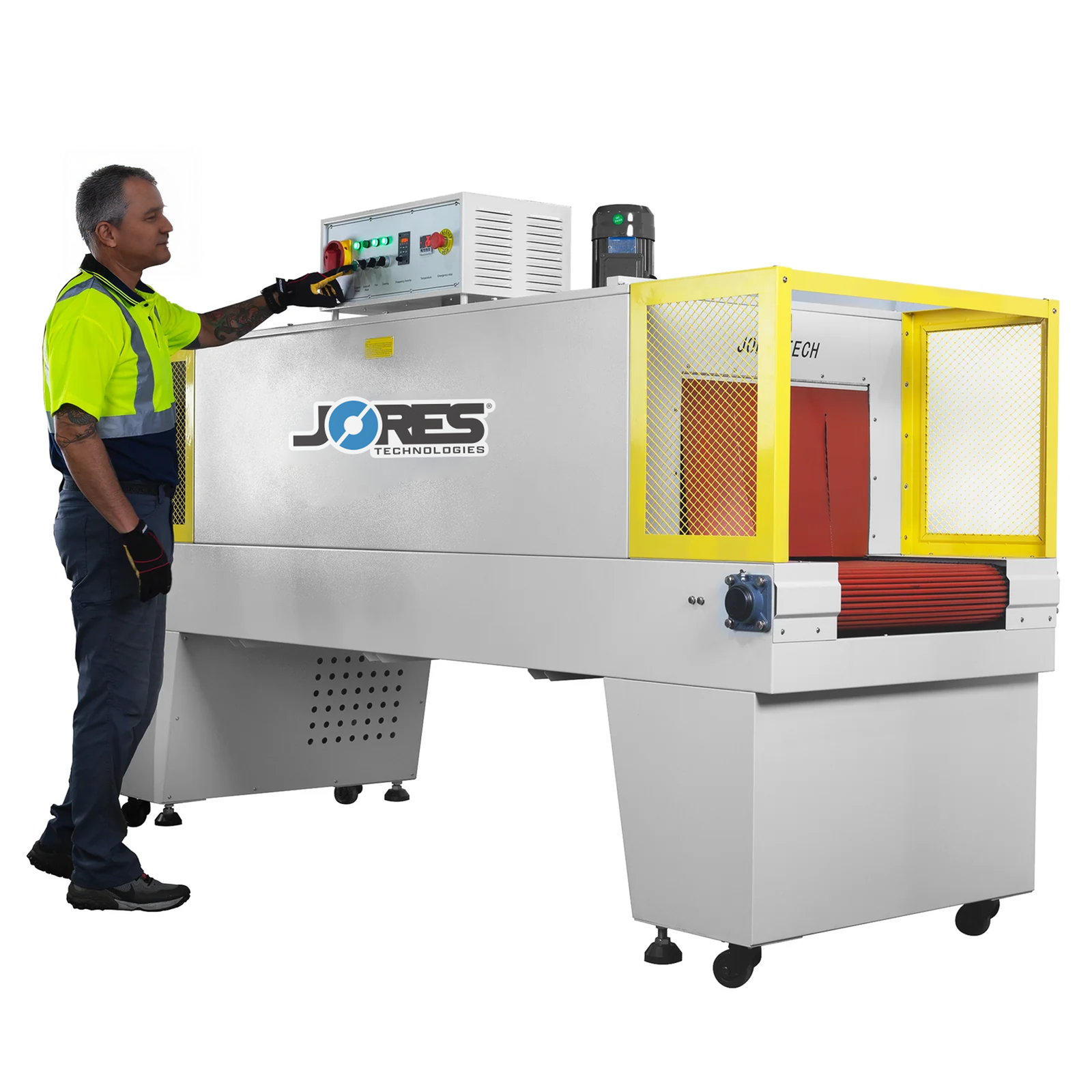 JORES TECHNOLOGIES® heat shrinking tunnel being operated by a man wearing a high visibility yellow shirt and high-impact safety glasses over a white background. He is pressing a button on the machine's control panel to stablish the conveyor's speed and temperature need in the tunnel. Three green lights on the control panel are lit up, machine is almost ready to start shrinking products.