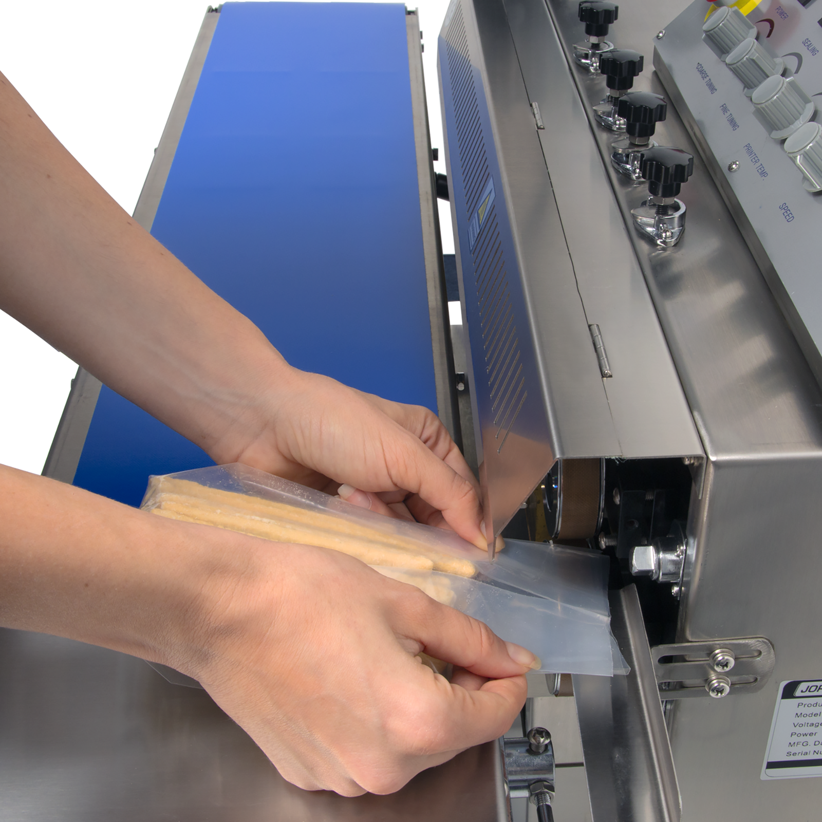 Hands of a person inserting a bag filled with bread sticks into the sealing track of a stainless steel digital horizontal continuous band sealer