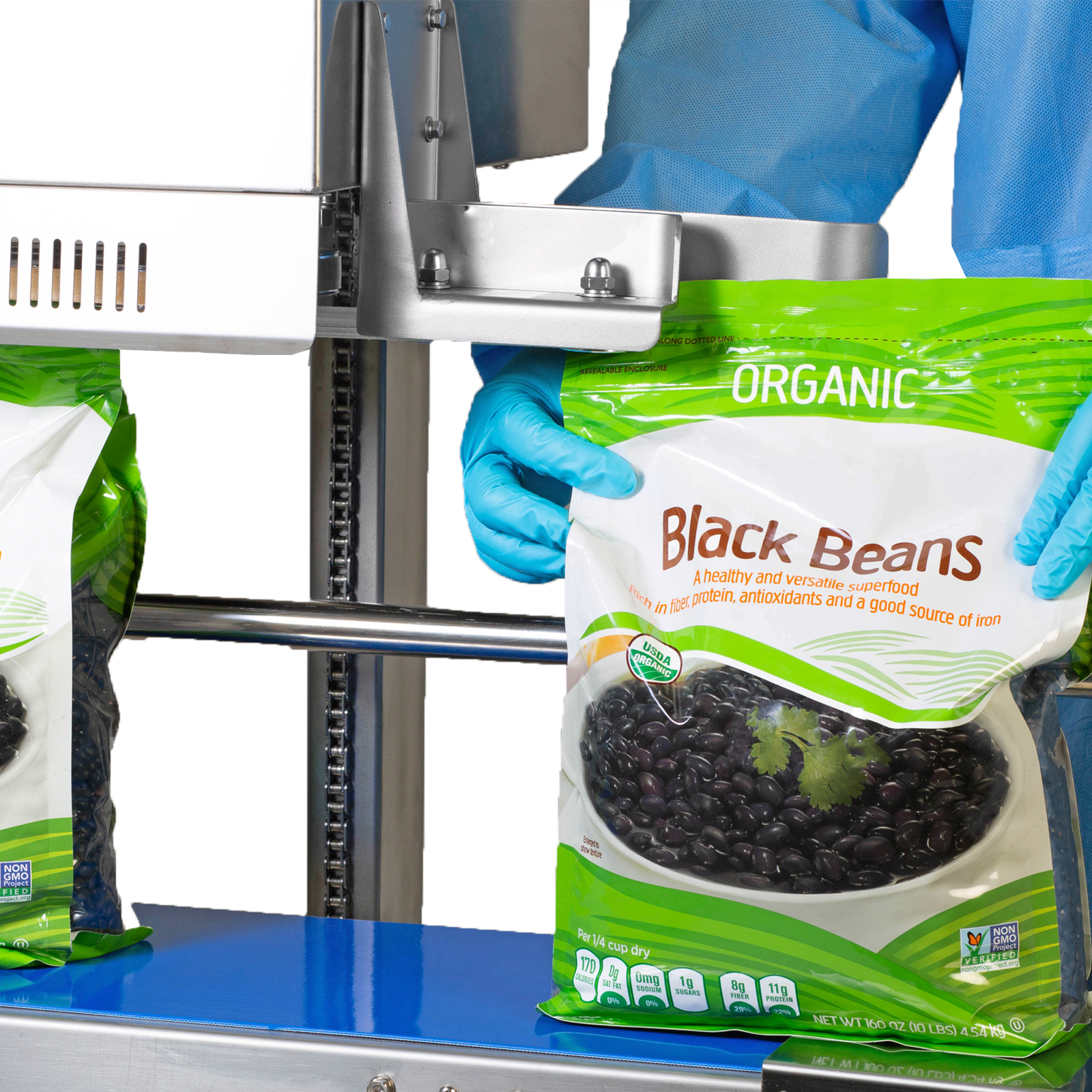 Operator wearing disposable blue clothing sealing and coding 10 pound large plastic bags filled with black beans with a vertical JORES TECHNOLOGIES® continuous band sealer for sealing vertically 