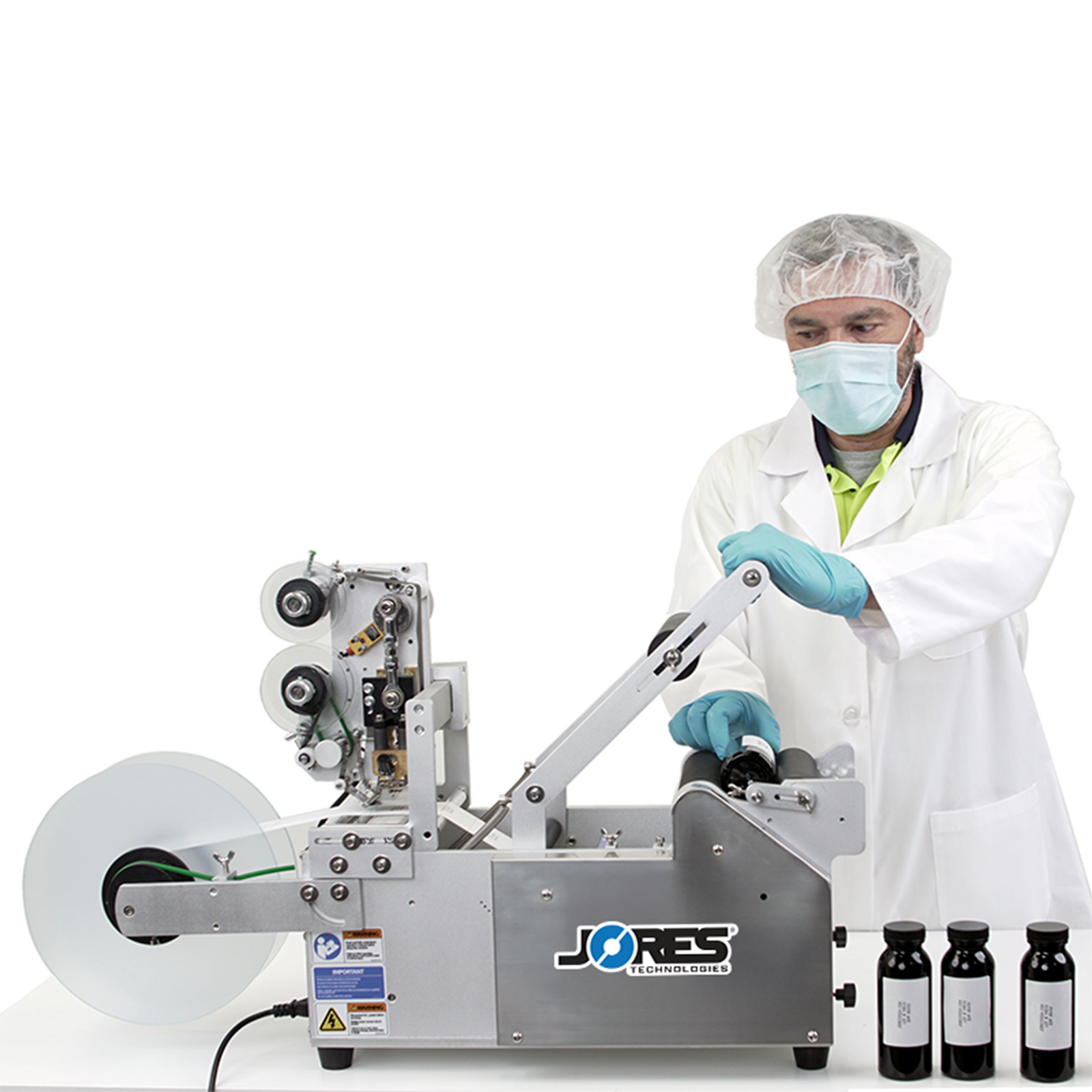 A man wearing personal protection equipment. He is operating the JORES TECHNOLOGIES® semi automatic labeling machine by applying labels to round containers. A set of 3 bottles is shown with printed labels with written information