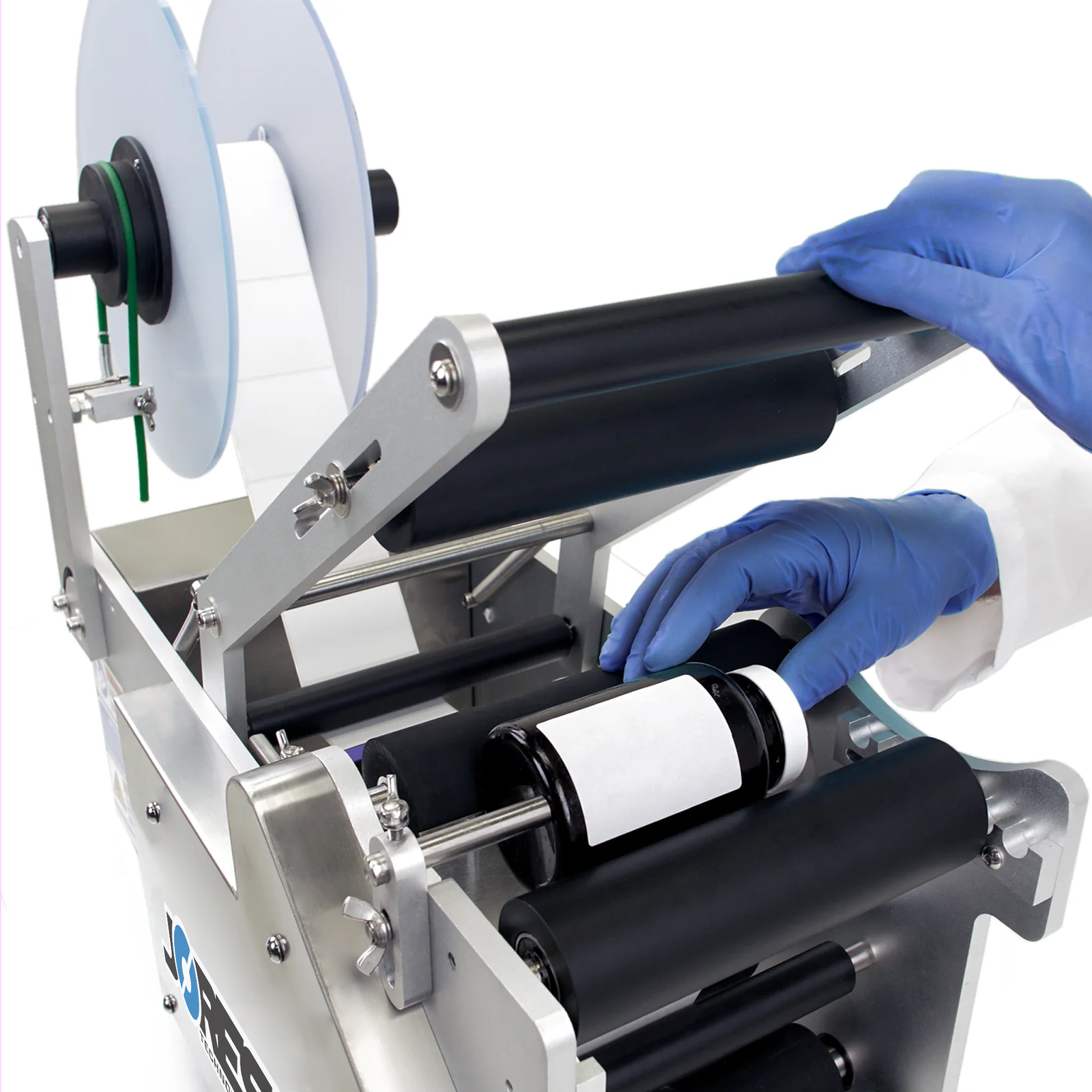 operator wearing nitrile blue gloves removing a labeled black bottle from semi-automatic label applicator