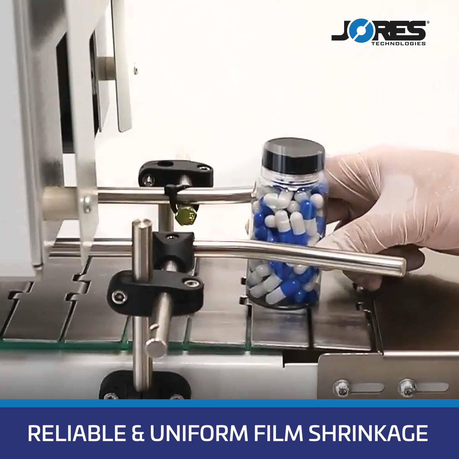 close up of the conveyor on a shrink tunnel for tamper proofing shows a hand wearing a white glove feeding a clear container with blue and white pills. Blue banner on the bottom with white text that reads reliable and uniform film shrinkage