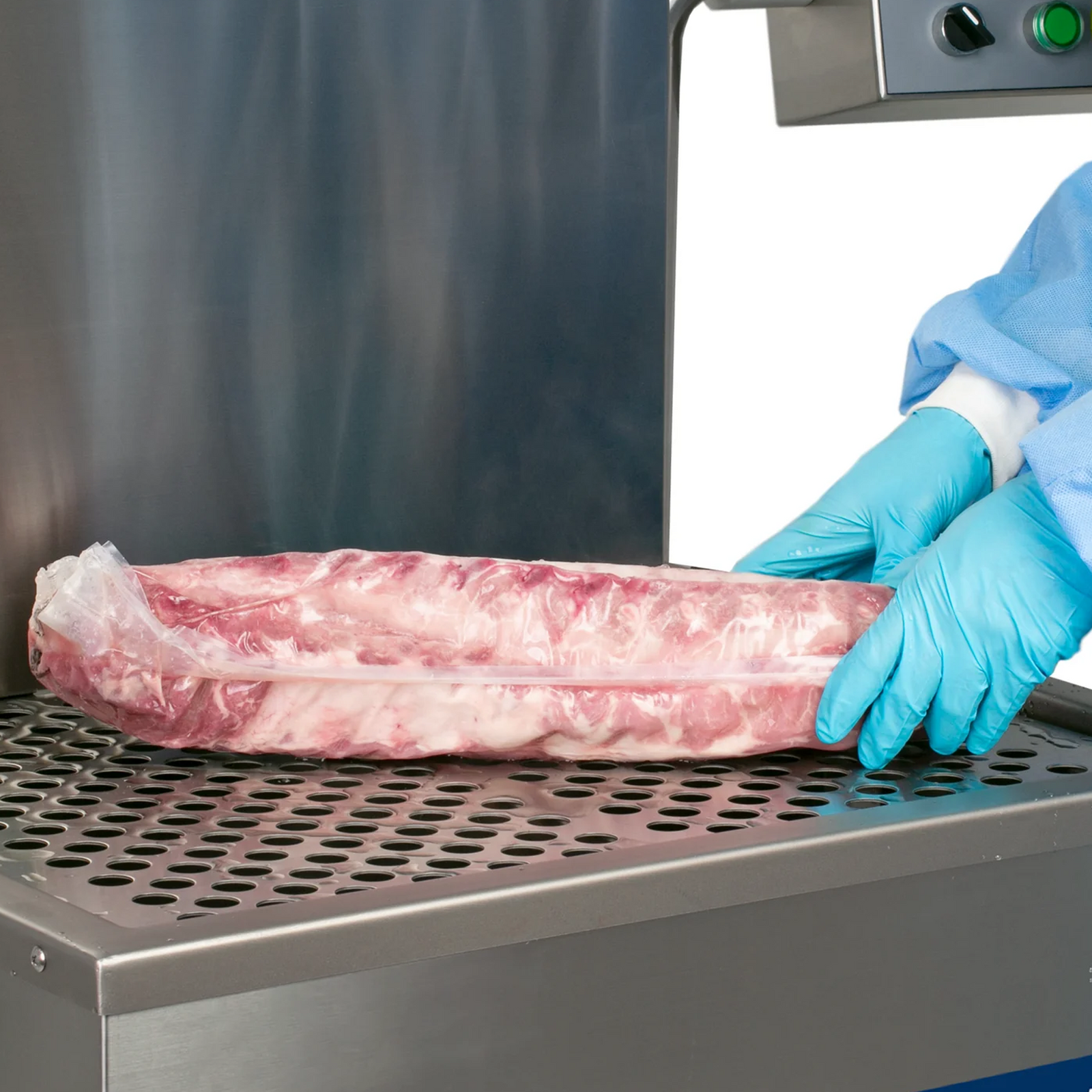 Hands of a person wearing disposable protective clothing removing a rack of ribs with shrink film vacuumed from the water tank of a JORES TECHNOLOGIES® semi-automatic dip style hot water shrink machine