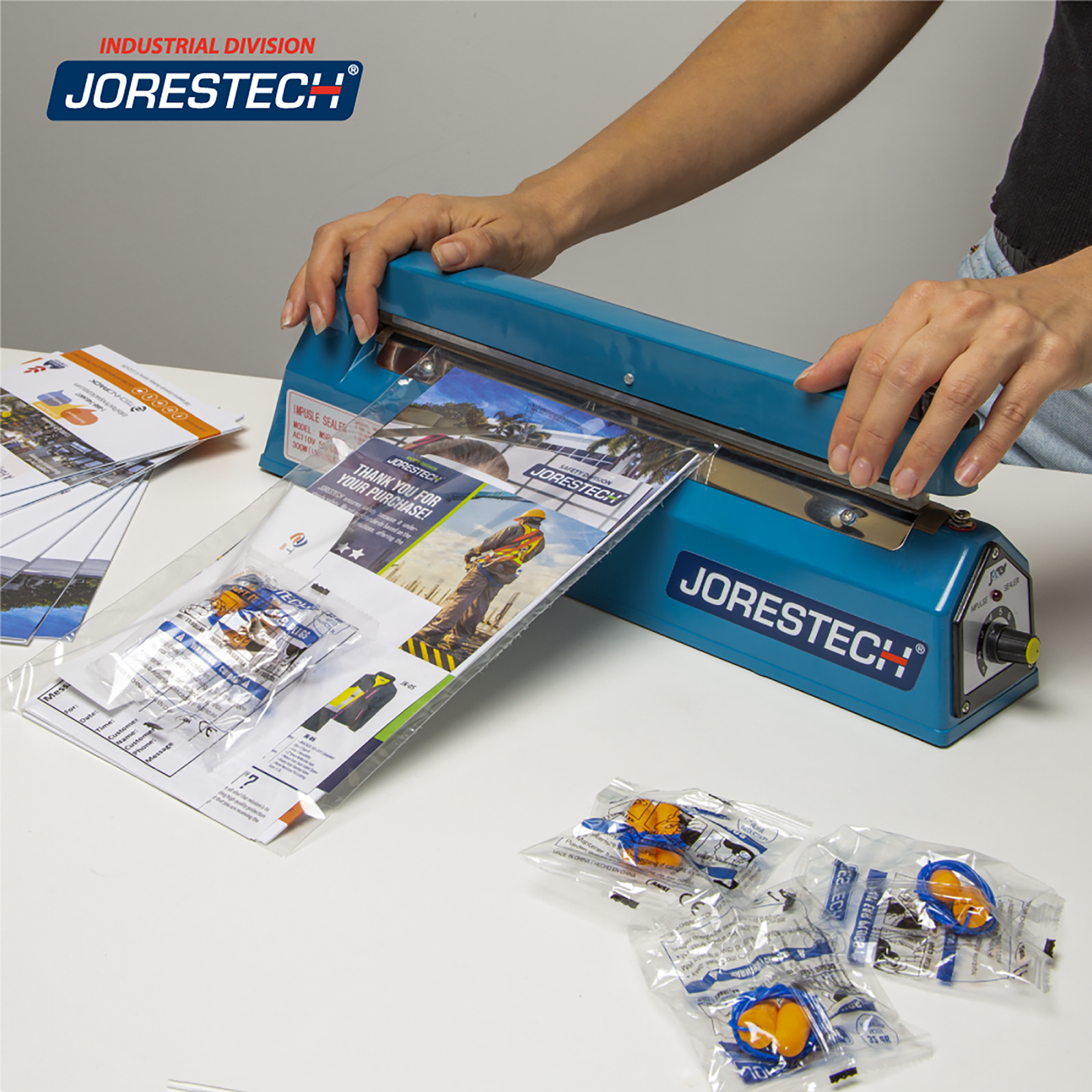 Person using the 12 inch manual impulse sealer to close a bags with a promotional packet bundle inside. 