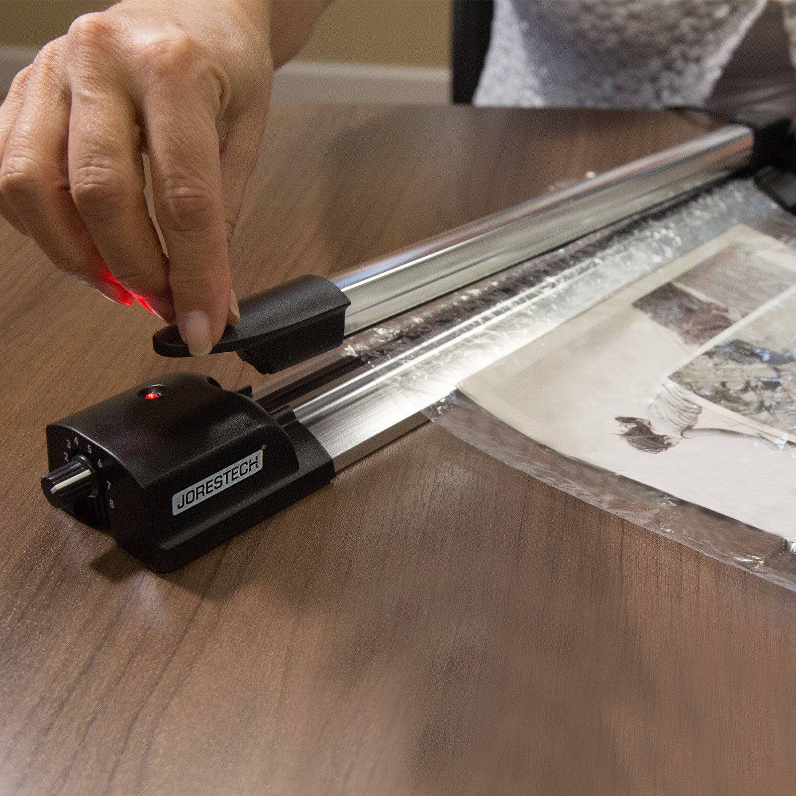 Manual Impulse sealer in action, sealing a bundle of documents inside of a plastic bag. Red light indicator is on, signaling that the bag sealer is currently sealing a bag