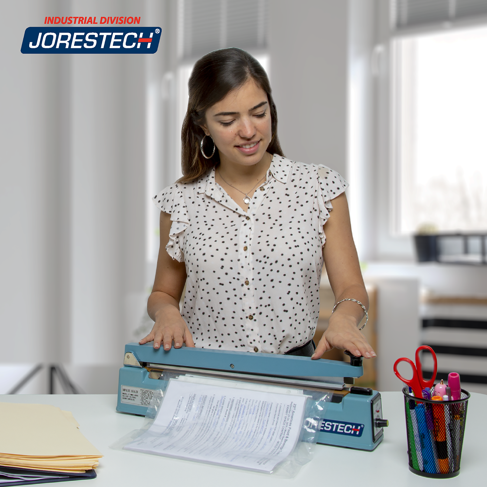 Young woman in an office setting working on top of a desk with a 16 inch manual impulse bag sealer sealing documents inside a heat sealable bags.