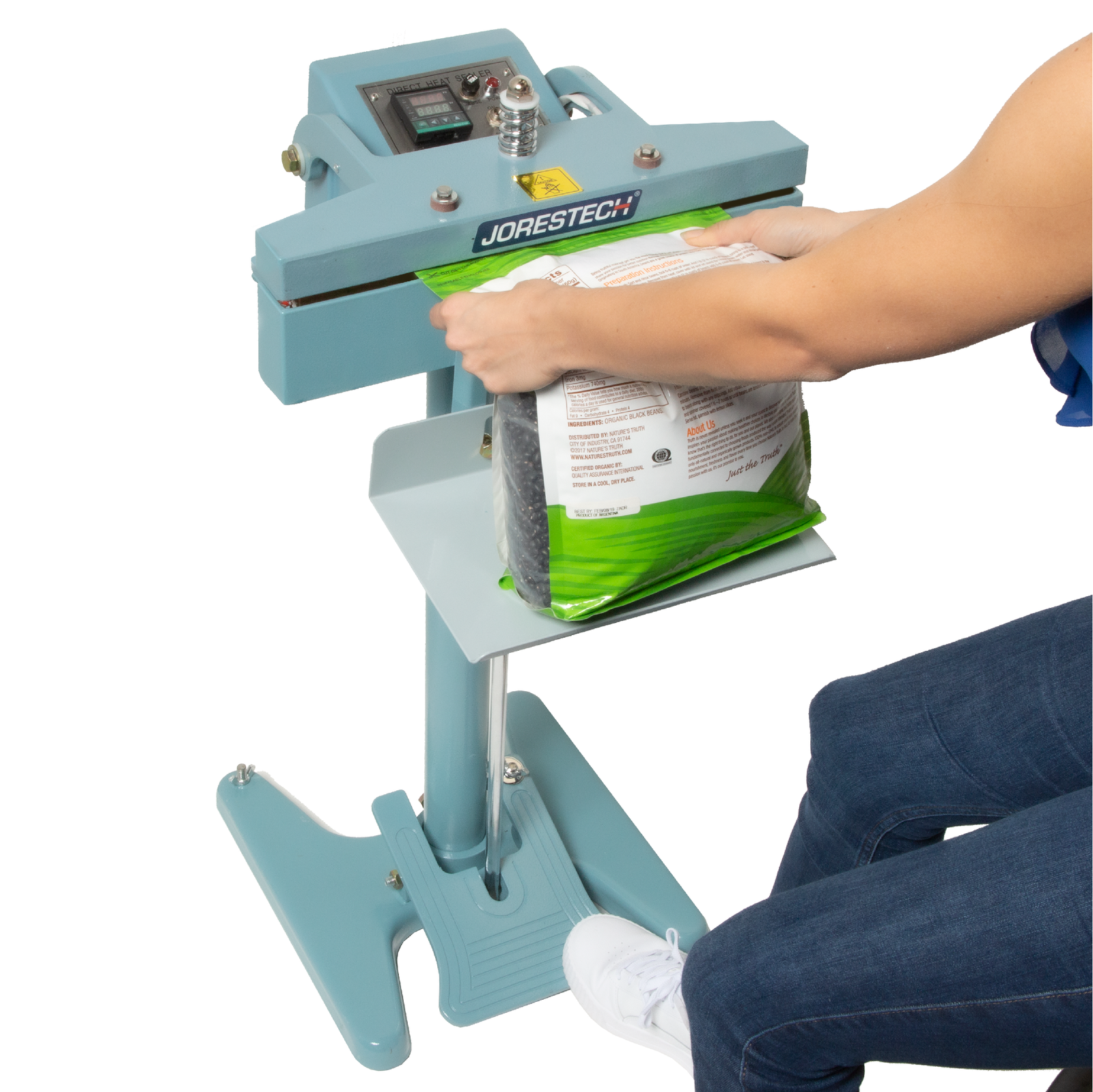 Worker stepping on the foot pedal of blue constant heat bag sealer to seal a heat sealable plastic bag