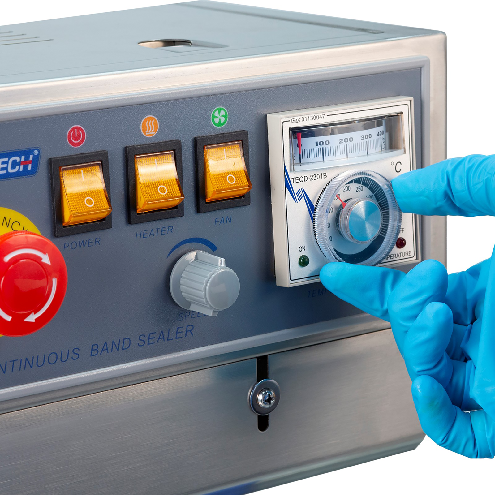 operator wearing blue gloves adjusting analog temperature control dial on the JORESTECH continuous band sealer