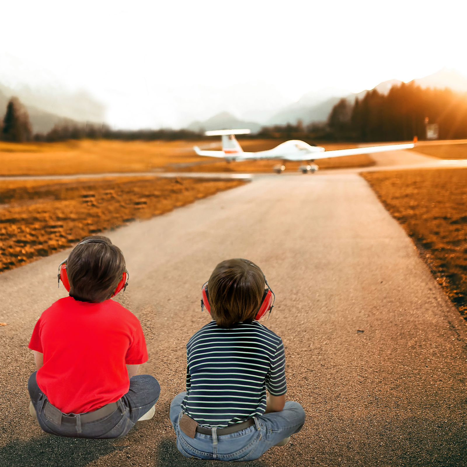 2 kids wearing ear muffs for hearing protection while watching airplanes take of and land from from an airport