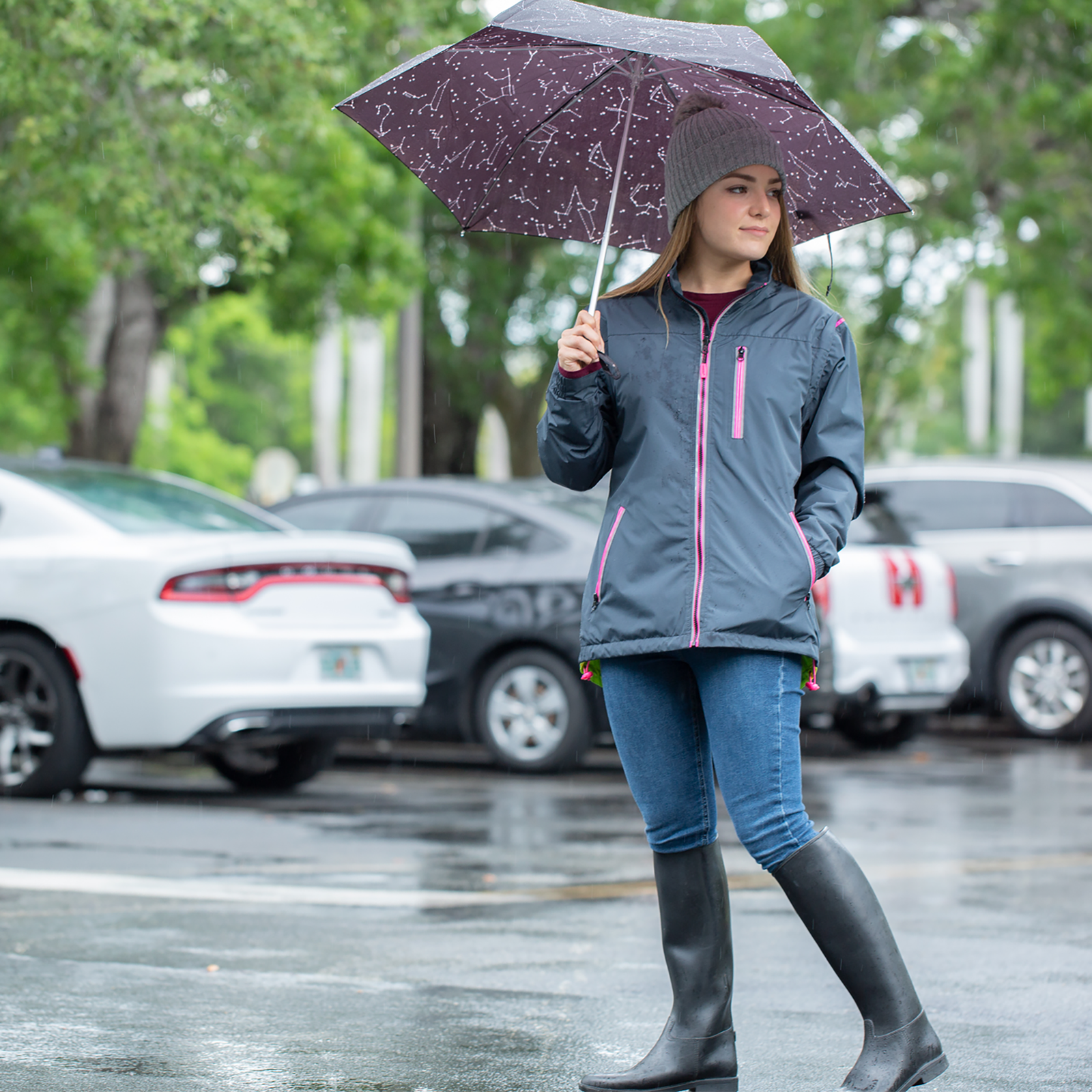 A woman wearing the non reflective side of  the JORESTECH light safety jacket in a parking lot looking for her car after work. 