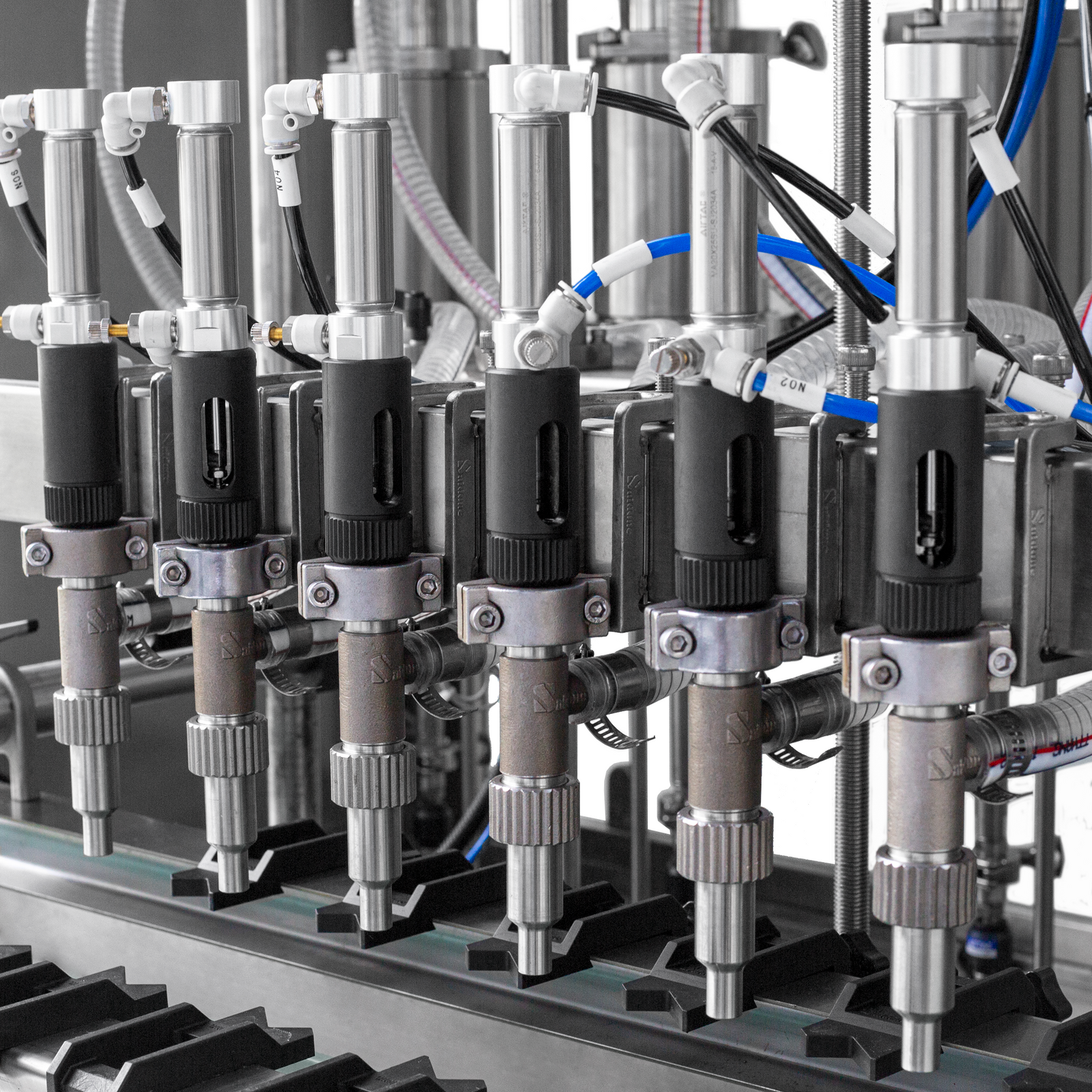 detailed closeup view of the 6 dispensing nozzles and the hose mechanism of the low viscosity Jorestech piston filling system