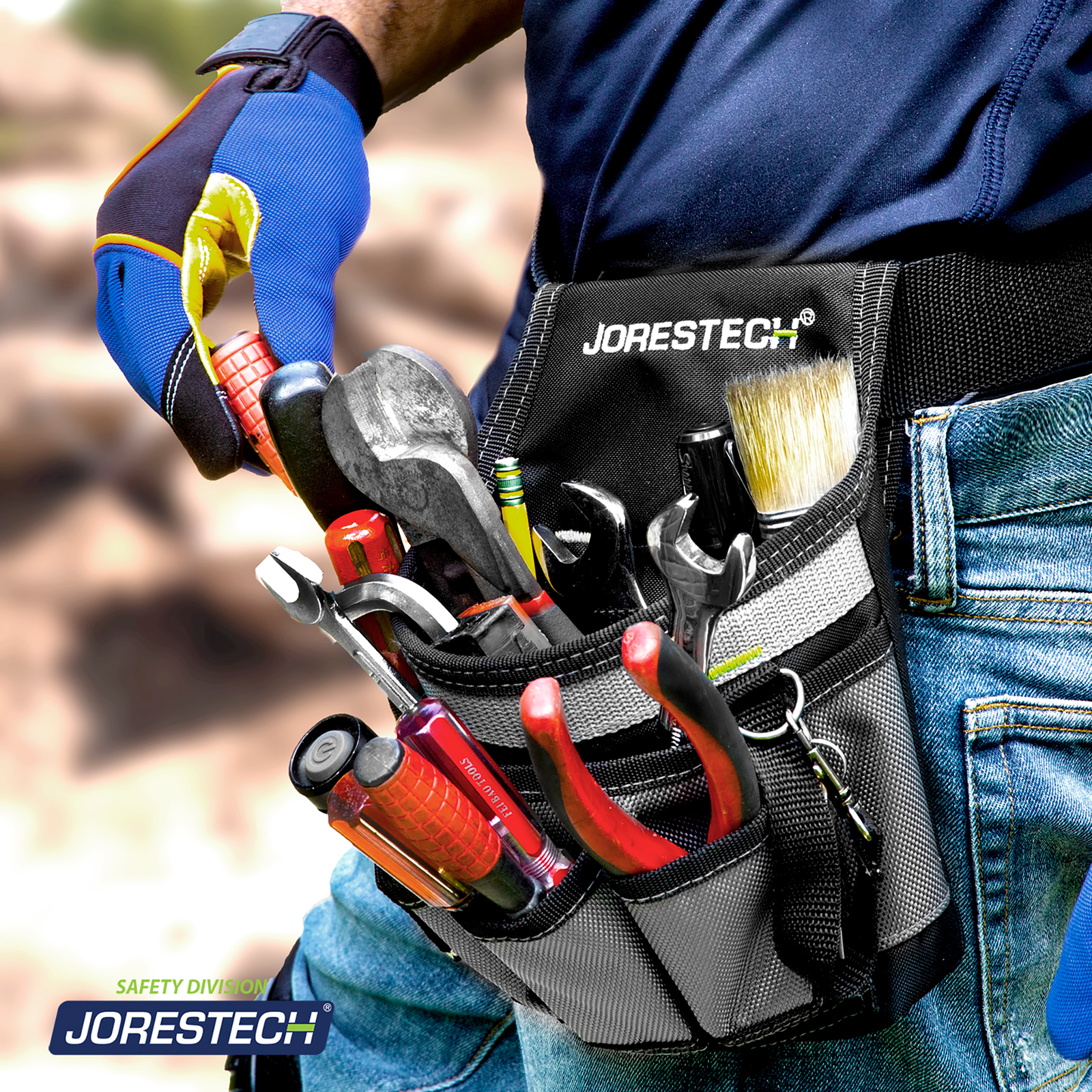 A worker wearing safety gloves accesing a screw driver form his  6 pocket tool belt pouch which is filled with tools while he is a a job site.